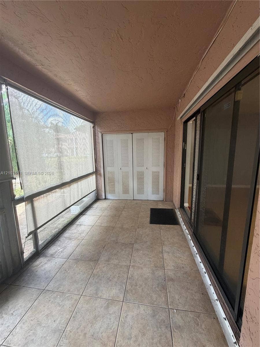 12 S Valencia Drive, #5-4, Davie, FL 33324 Screened-in patio featuring tile flooring, louvered-style closet doors, and sliding glass entry doors
