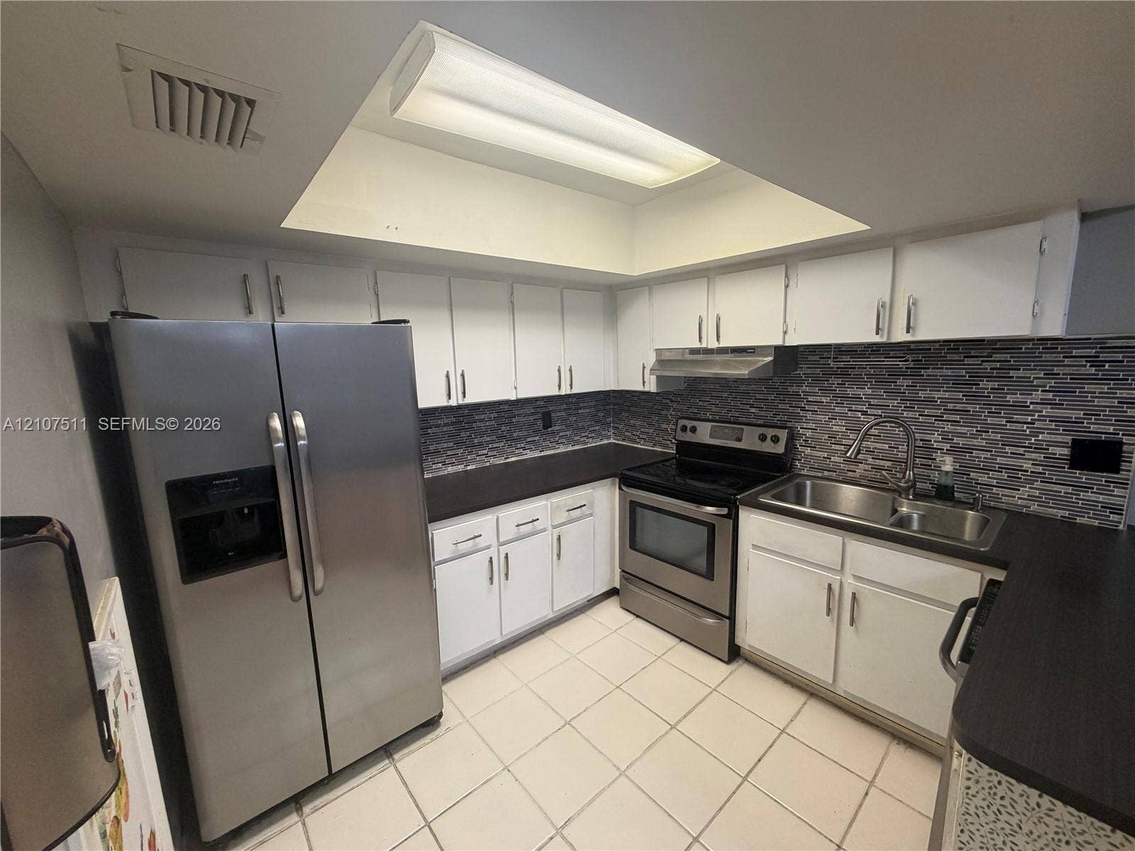 12 S Valencia Drive, #5-4, Davie, FL 33324 Kitchen featuring white cabinetry, stainless steel appliances, dark countertops, mosaic tile backsplash, and a recessed ceiling light fixture