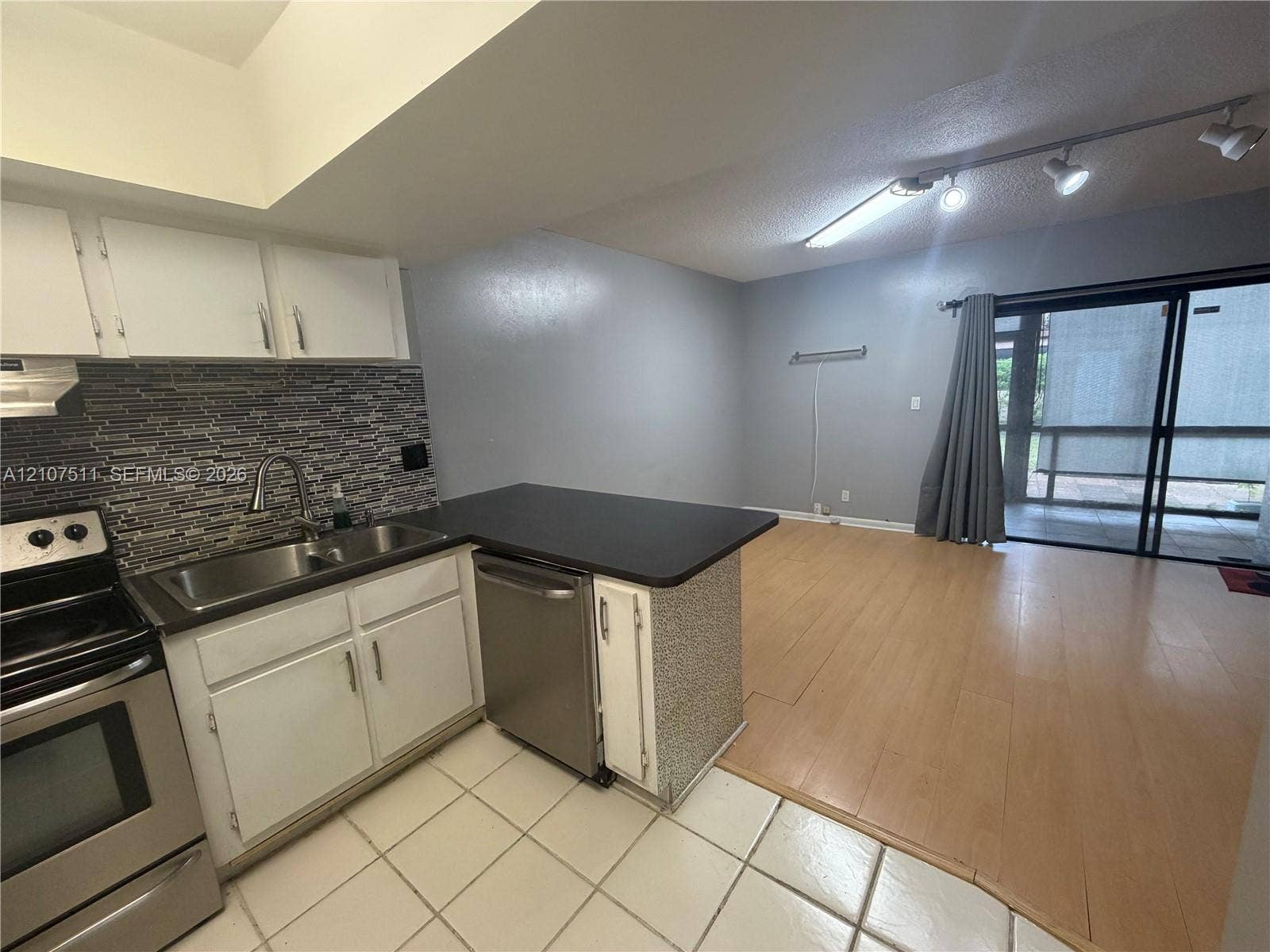 12 S Valencia Drive, #5-4, Davie, FL 33324 Kitchen featuring stainless steel appliances, multi-toned decorative tile backsplash, wood-finish flooring, and sliding glass doors