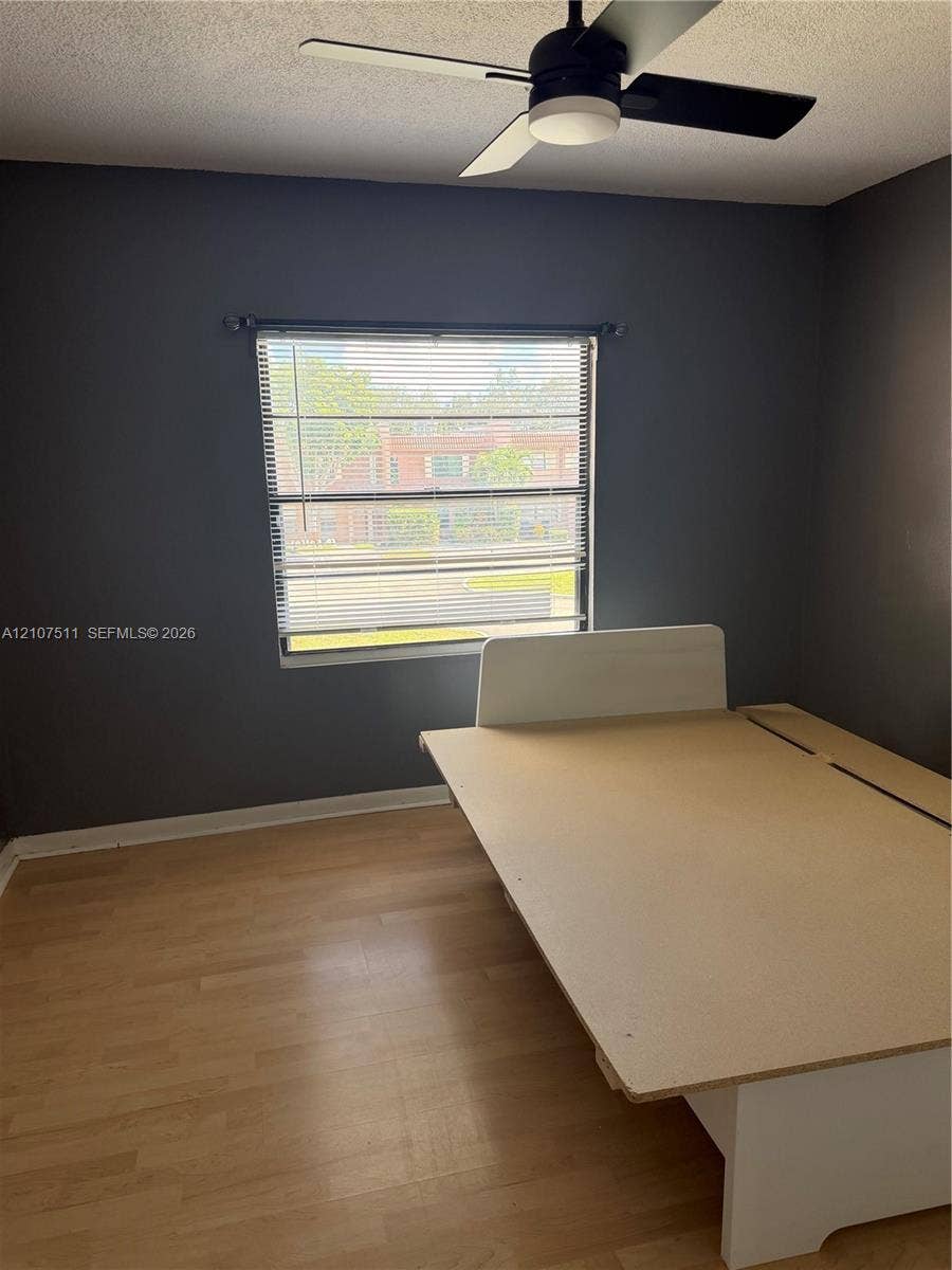 12 S Valencia Drive, #5-4, Davie, FL 33324 Room featuring wood-finish flooring, dark-toned walls, and a ceiling-mounted fan with integrated lighting