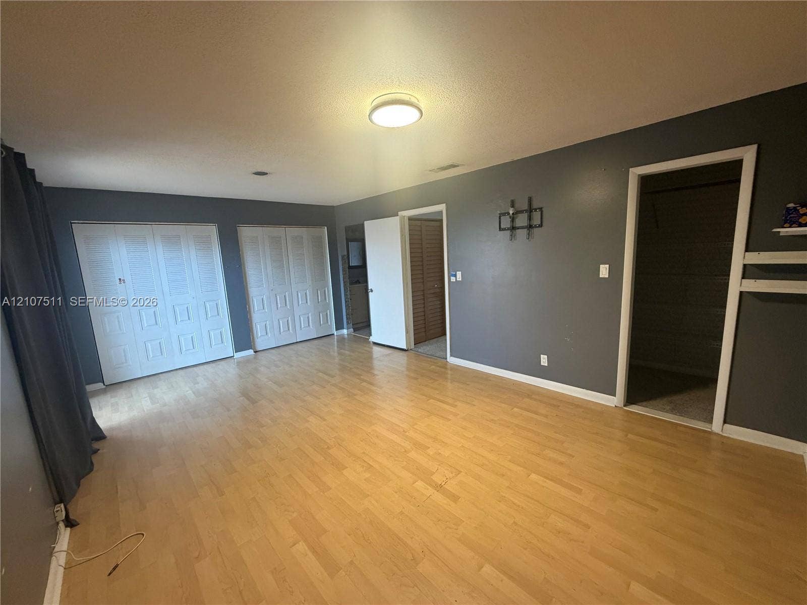 12 S Valencia Drive, #5-4, Davie, FL 33324 Room featuring wood-finish flooring, two sets of white louvered closet doors, and interior access to a secondary space
