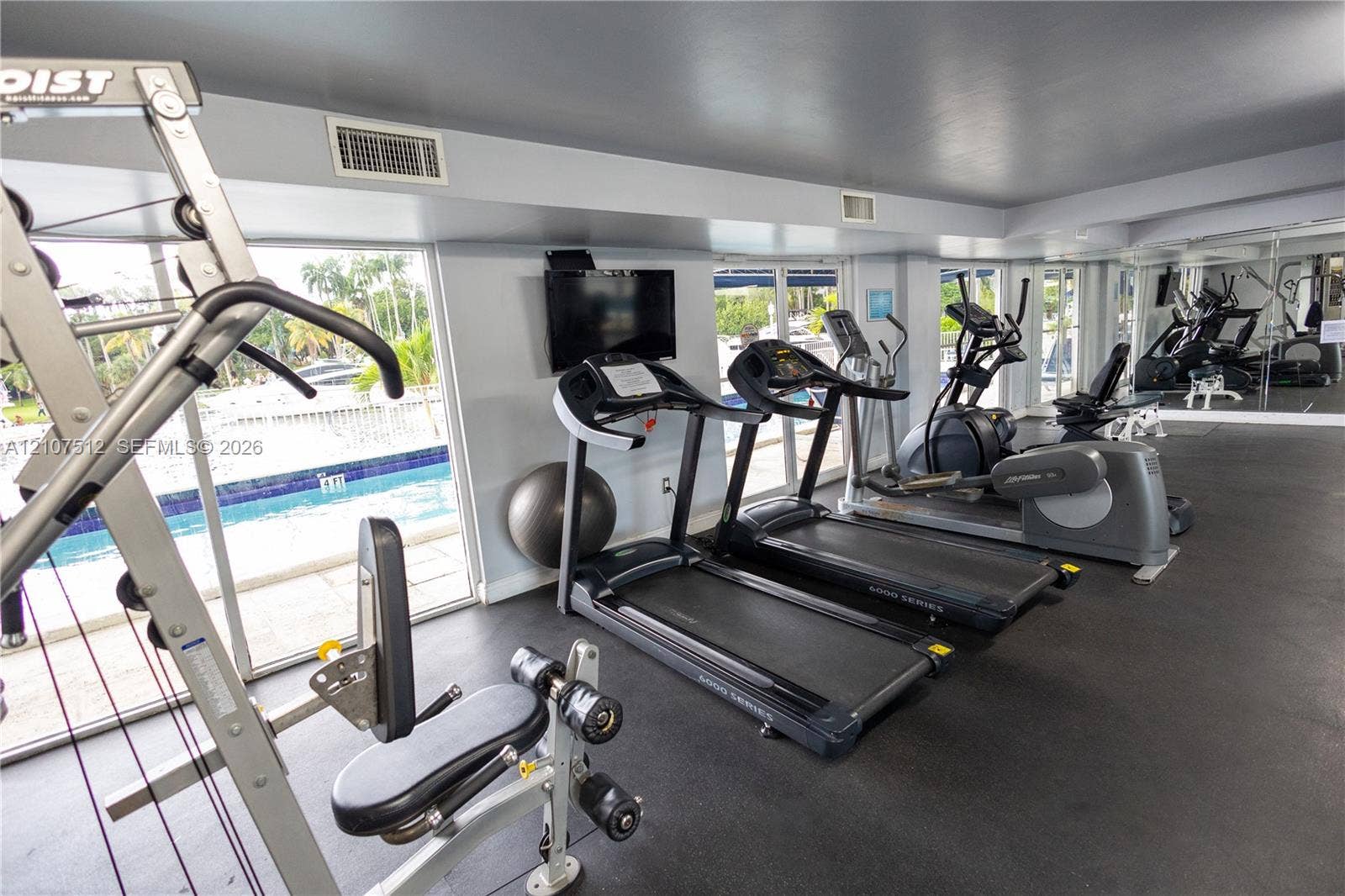 1720 N River Drive, #302, Miami, FL 33125 Fitness center featuring durable rubber flooring, floor-to-ceiling windows, wall-mounted television, and mirrored walls