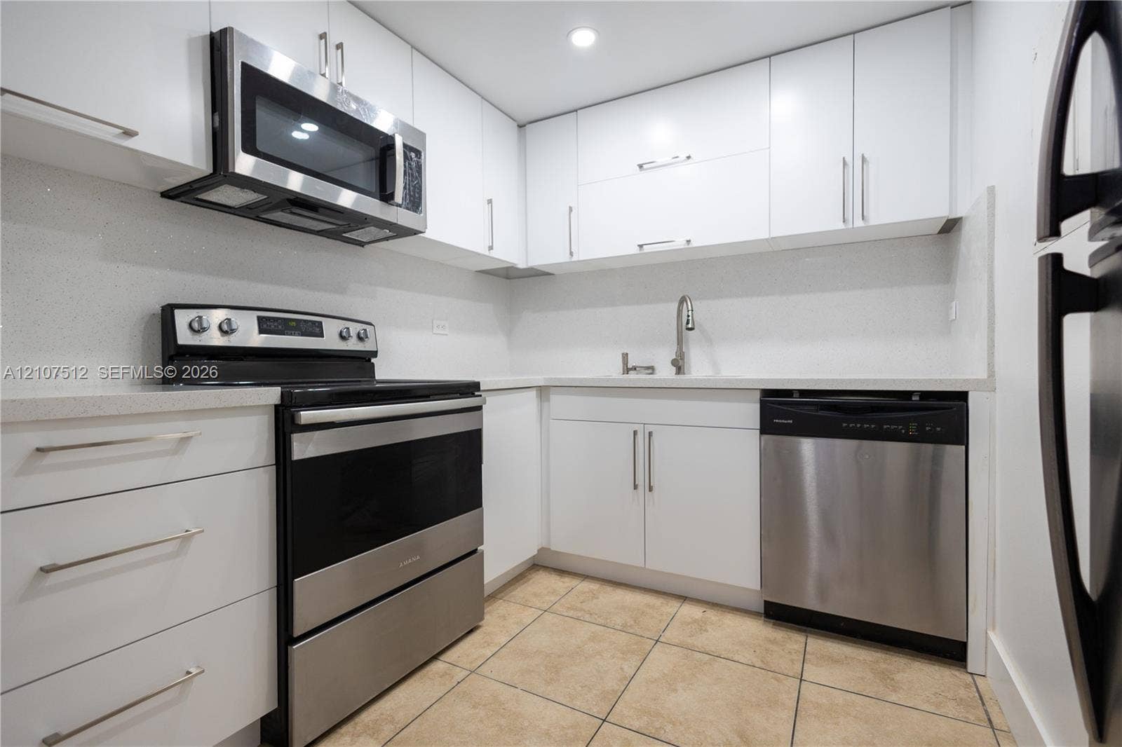 1720 N River Drive, #302, Miami, FL 33125 Kitchen featuring white flat-panel cabinetry, stainless steel appliances, solid surface countertops, a gooseneck faucet, and tiled flooring