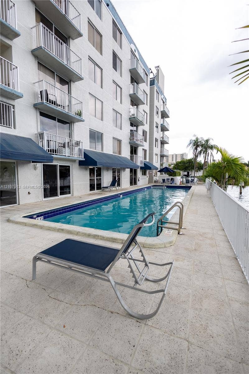 1720 N River Drive, #302, Miami, FL 33125 In-ground swimming pool with a stone-paver deck, blue canvas retractable awnings, and multi-level balconies