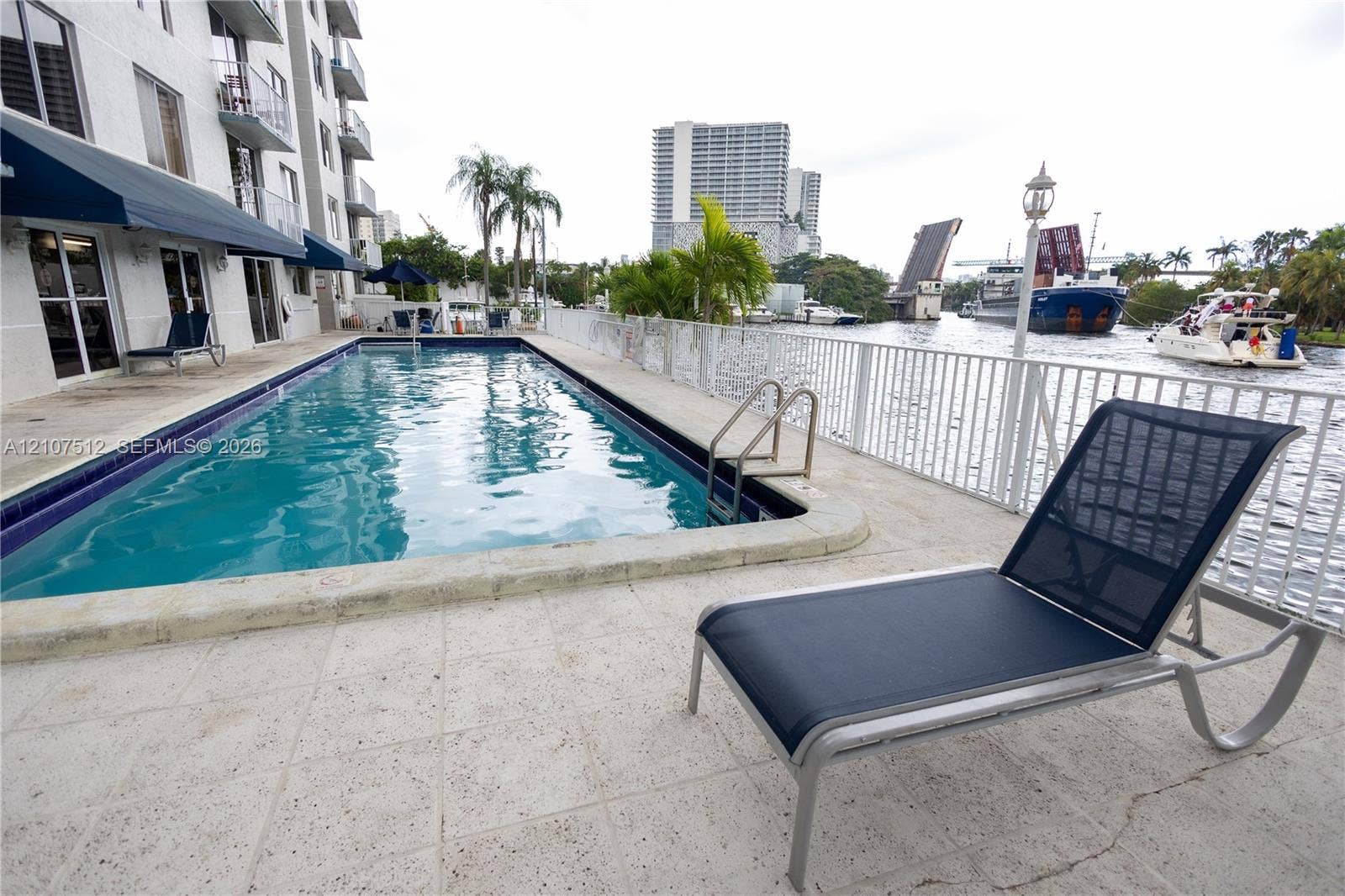 1720 N River Drive, #302, Miami, FL 33125 Rectangular swimming pool with a stone deck, perimeter safety fencing, and direct water frontage