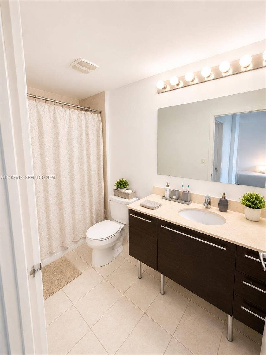1900 N Bayshore Drive, #3005, Miami, FL 33132 Bathroom featuring a dark wood-finish vanity with metal legs, a solid surface countertop with an integrated oval sink, a large wall-mounted mirror, and a multi-bulb light fixture