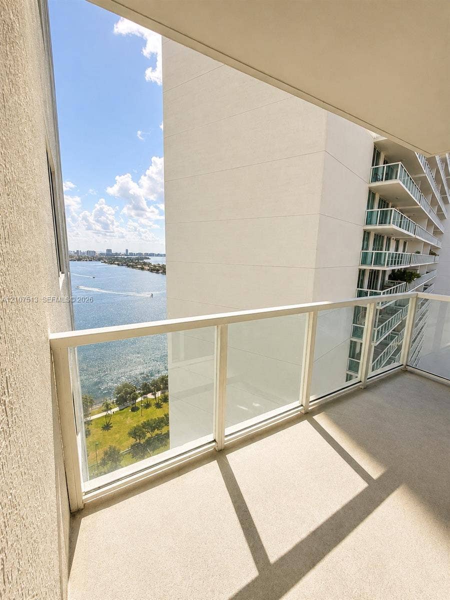 1900 N Bayshore Drive, #3005, Miami, FL 33132 Private balcony featuring a glass-panel railing and concrete flooring, overlooking the water and shoreline