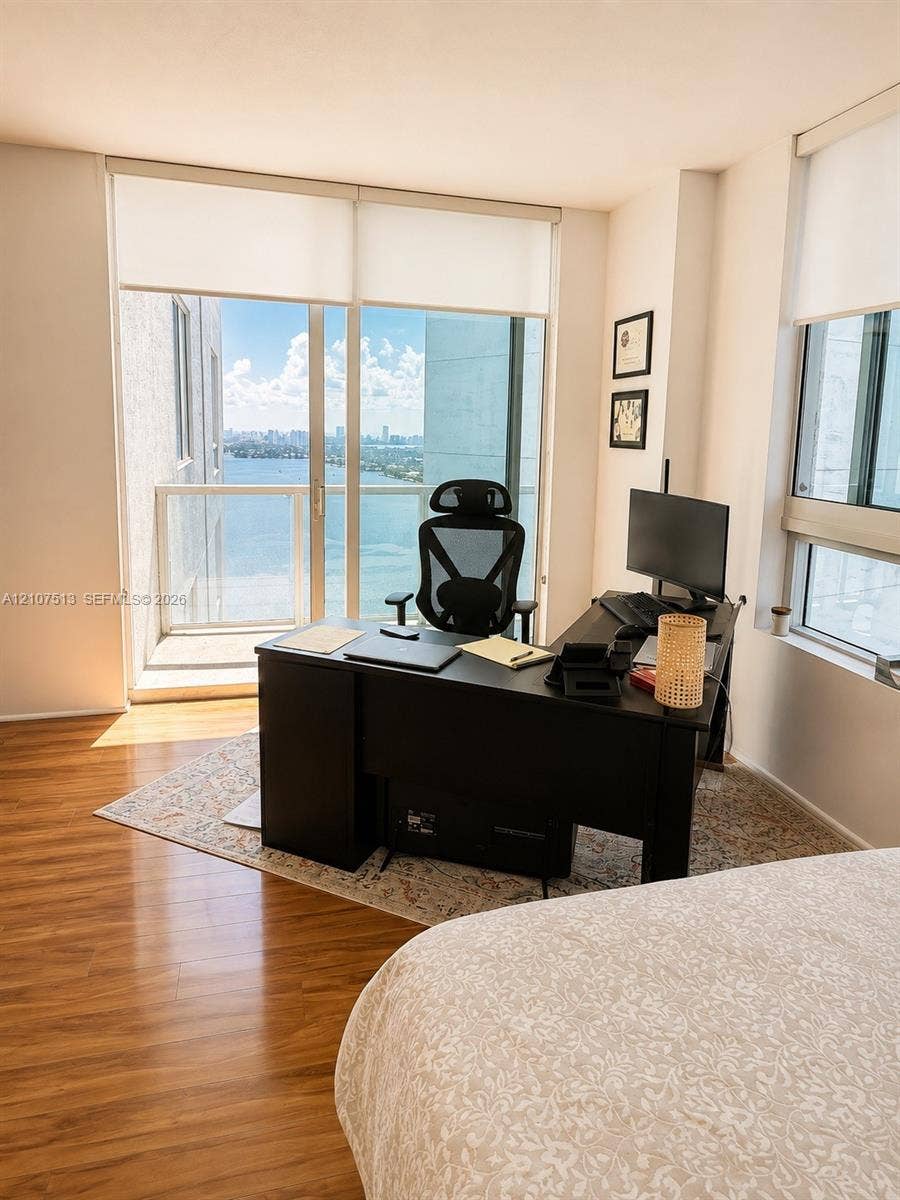 1900 N Bayshore Drive, #3005, Miami, FL 33132 Floor-to-ceiling windows, wood-finish flooring, and a private balcony featuring metal and glass railings with coastal and urban scenery