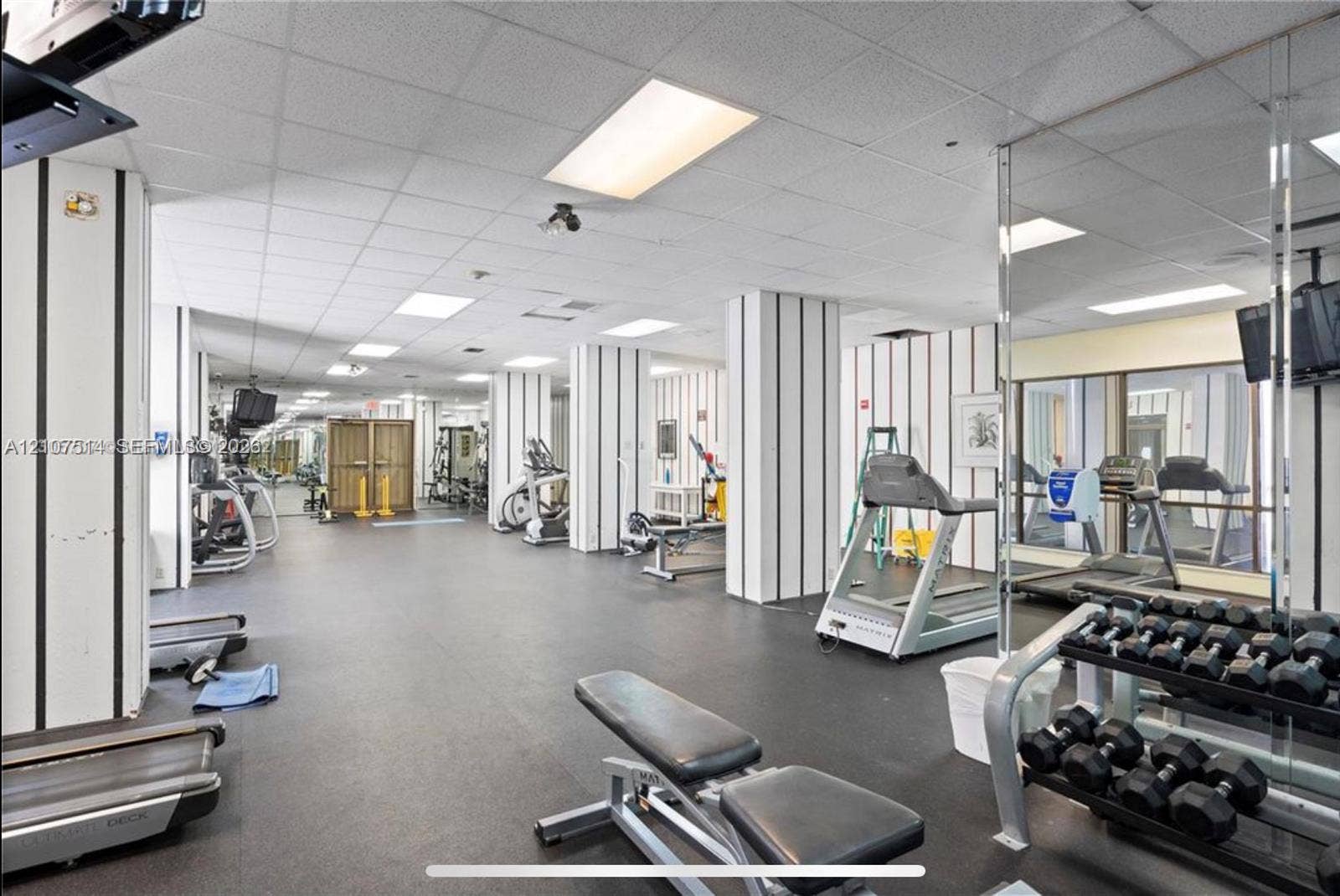 2750 NE 183rd Street, #2310, Aventura, Aventura, FL 33160 Fitness facility featuring rubberized flooring, mirrored walls, drop ceiling panels, and structural columns with vertical accent detailing