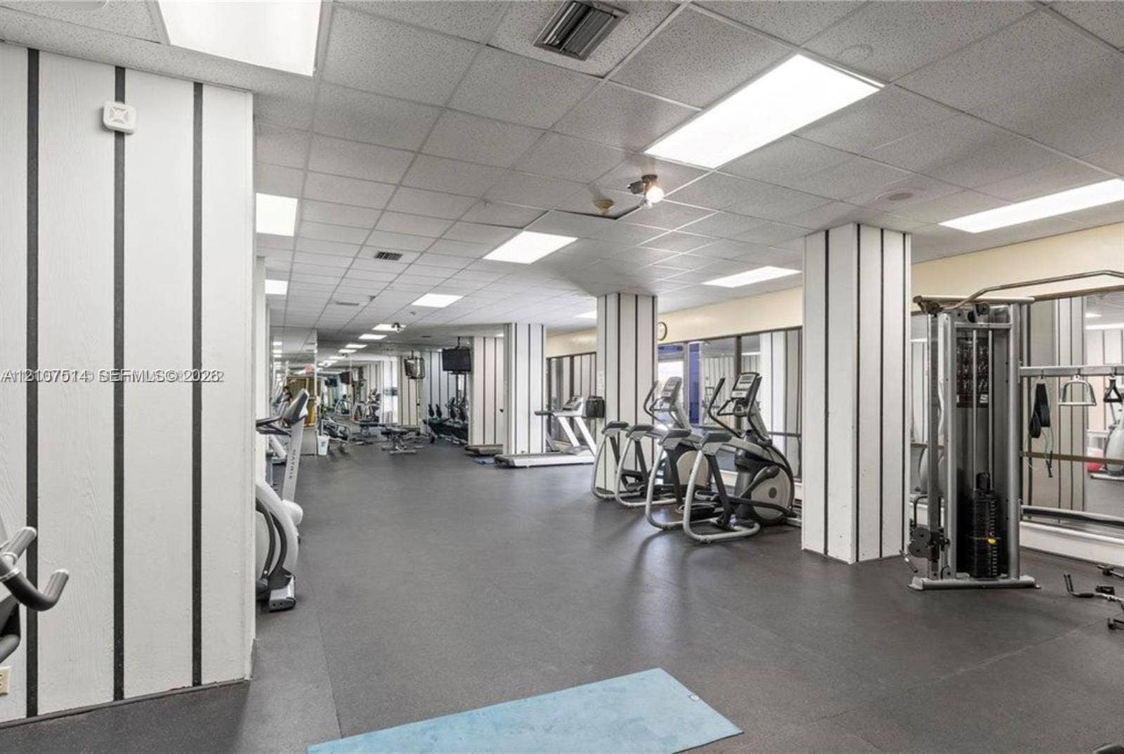 2750 NE 183rd Street, #2310, Aventura, Aventura, FL 33160 Fitness center featuring black-and-white vertical wall paneling, a suspended drop ceiling with recessed lighting, integrated wall mirrors, and rubberized athletic flooring