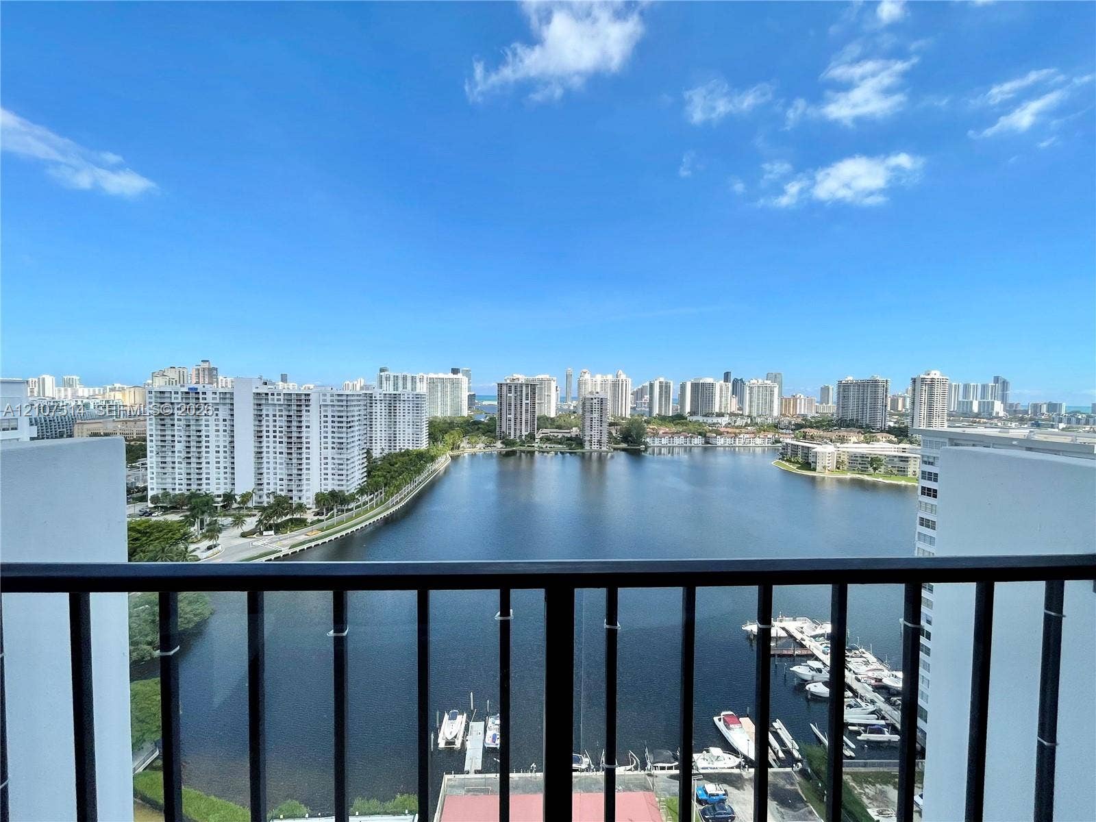 2750 NE 183rd Street, #2310, Aventura, Aventura, FL 33160 Elevated balcony featuring a black metal railing, overlooking a large waterway, boat slips, and a cityscape skyline