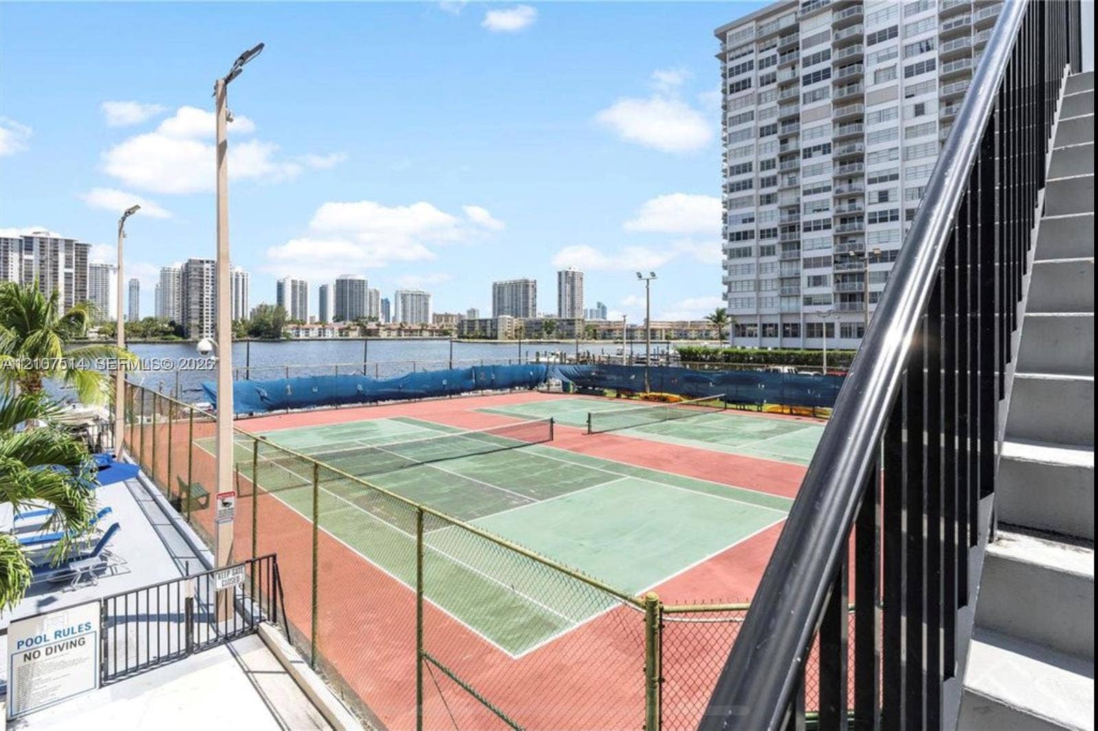 2750 NE 183rd Street, #2310, Aventura, Aventura, FL 33160 Tennis courts with chain-link fencing, paved surfaces, and net systems positioned near the water