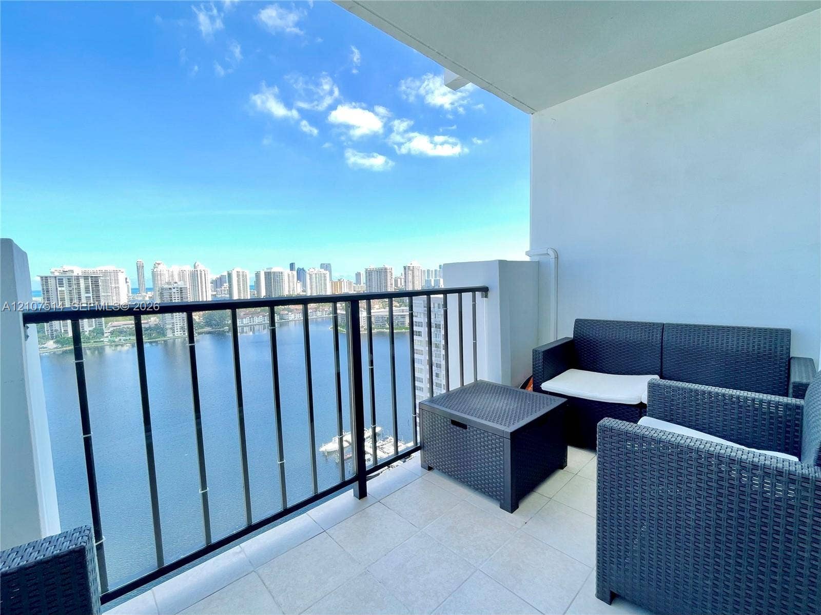 2750 NE 183rd Street, #2310, Aventura, Aventura, FL 33160 Covered balcony featuring tile flooring and a black metal railing overlooking the water and urban skyline