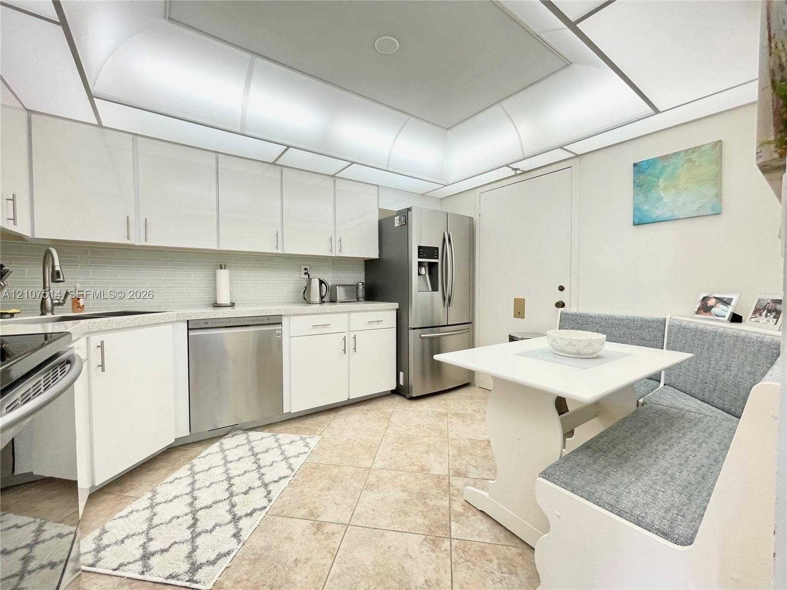 2750 NE 183rd Street, #2310, Aventura, Aventura, FL 33160 Kitchen featuring white cabinetry, stainless steel appliances, light-toned stone-finish countertops, tiled backsplash, and recessed cove lighting