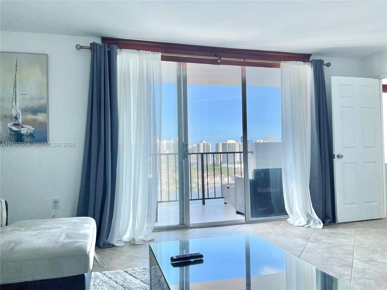 2750 NE 183rd Street, #2310, Aventura, Aventura, FL 33160 Sliding glass doors with a wooden valance, tile flooring, and a covered balcony featuring metal railings and urban skyline scenery