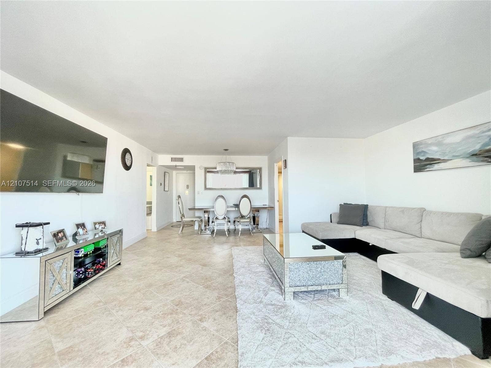 2750 NE 183rd Street, #2310, Aventura, Aventura, FL 33160 Open-concept living space featuring large-format ceramic tile flooring, neutral wall finishes, and a contemporary multi-light chandelier
