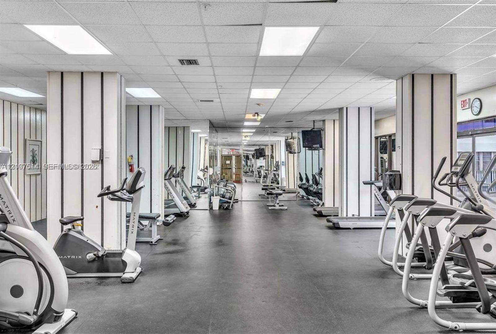 2750 NE 183rd Street, #2310, Aventura, Aventura, FL 33160 Fitness room featuring rubberized flooring, drop ceiling with recessed panel lighting, mirrored wall accents, and vertical pinstripe wall detailing