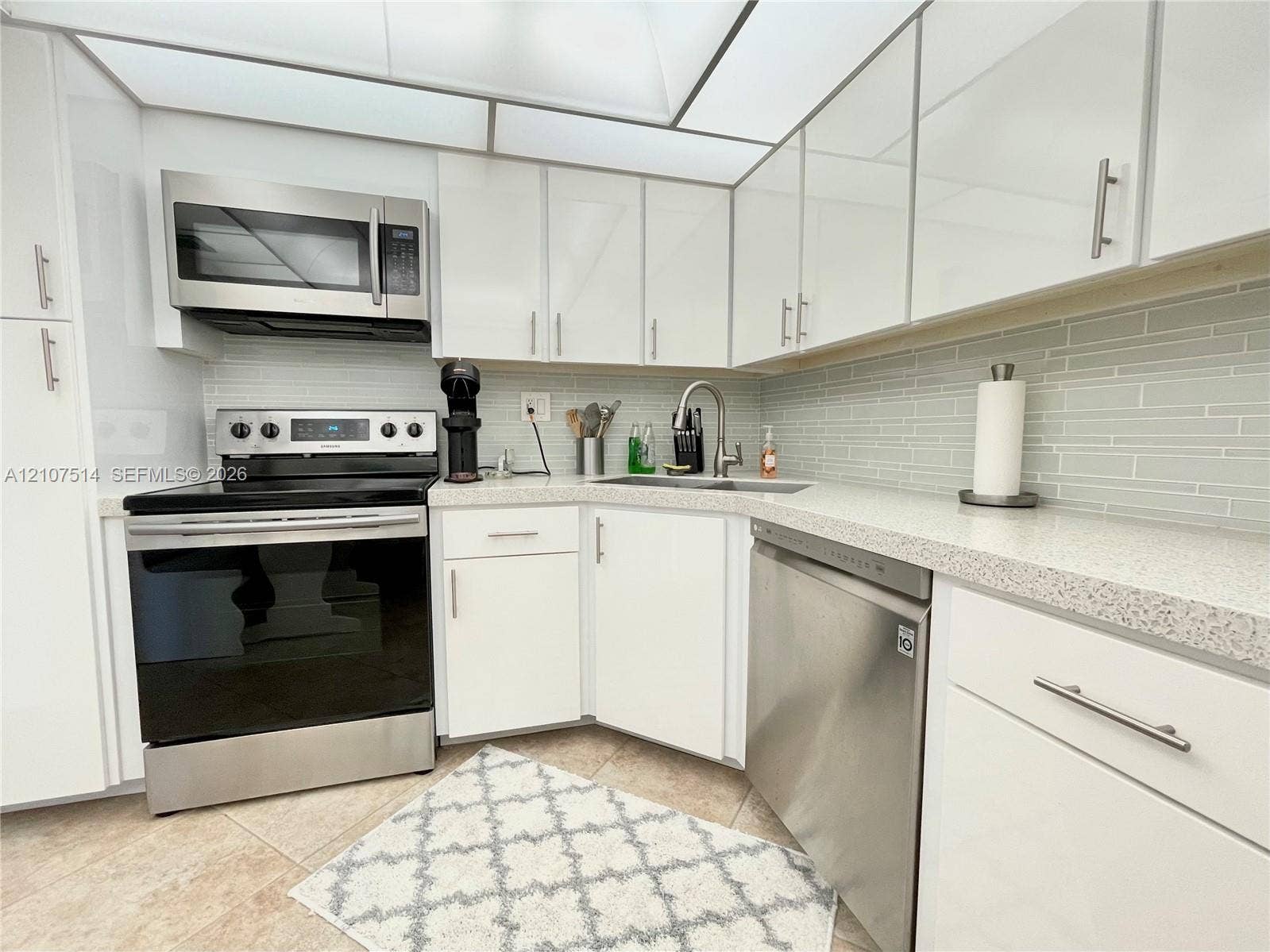 2750 NE 183rd Street, #2310, Aventura, Aventura, FL 33160 Kitchen featuring white cabinetry with metallic hardware, stone-composite countertops, stainless steel appliances, and a glass-tile backsplash