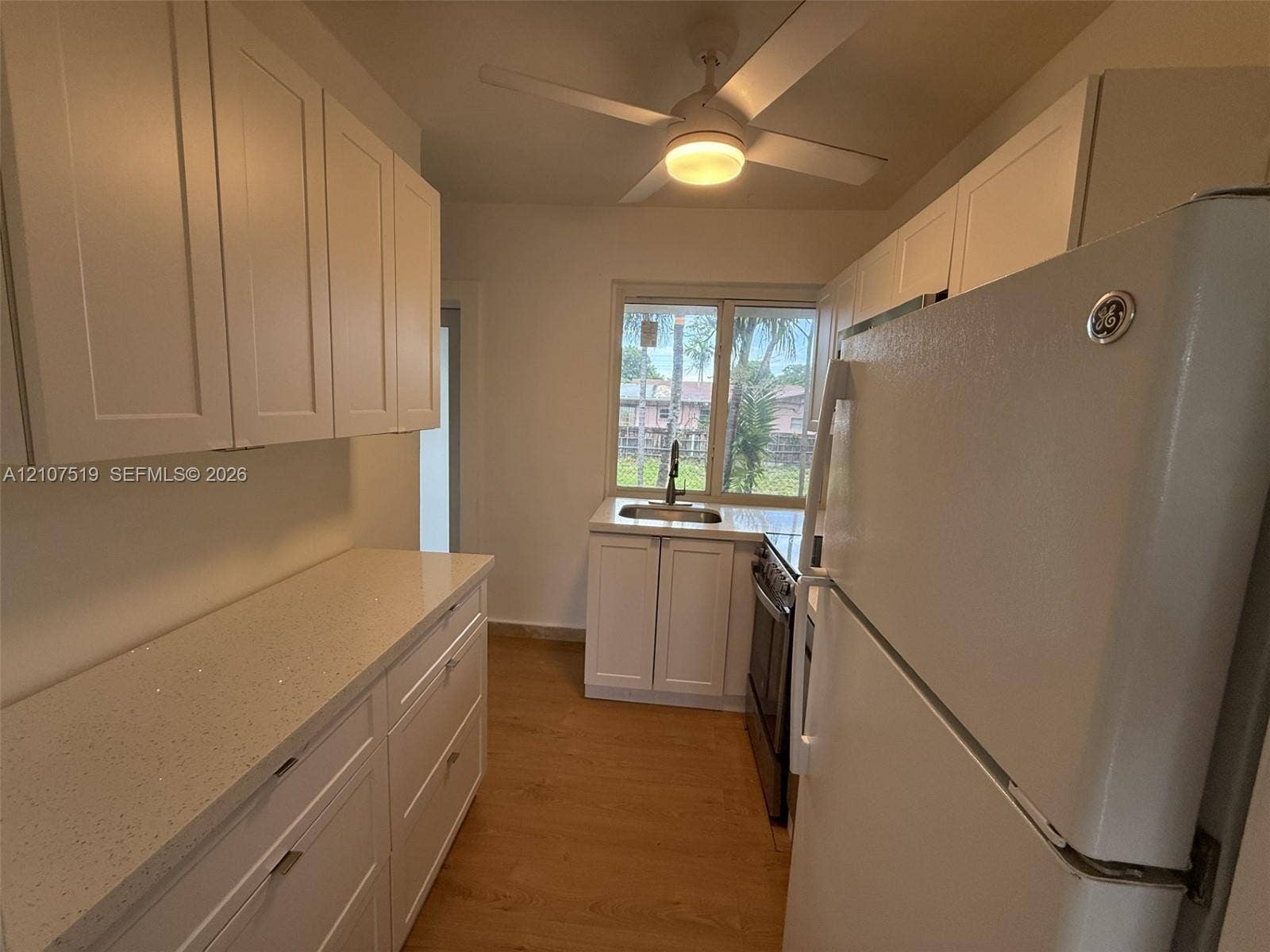 1201 SW 13th Street, #1205, Miami, Miami, FL 33145 Kitchen featuring white Shaker-style cabinetry, light-toned speckled countertops, wood-finish flooring, a stainless steel sink, and a ceiling-mounted light fixture with integrated fan