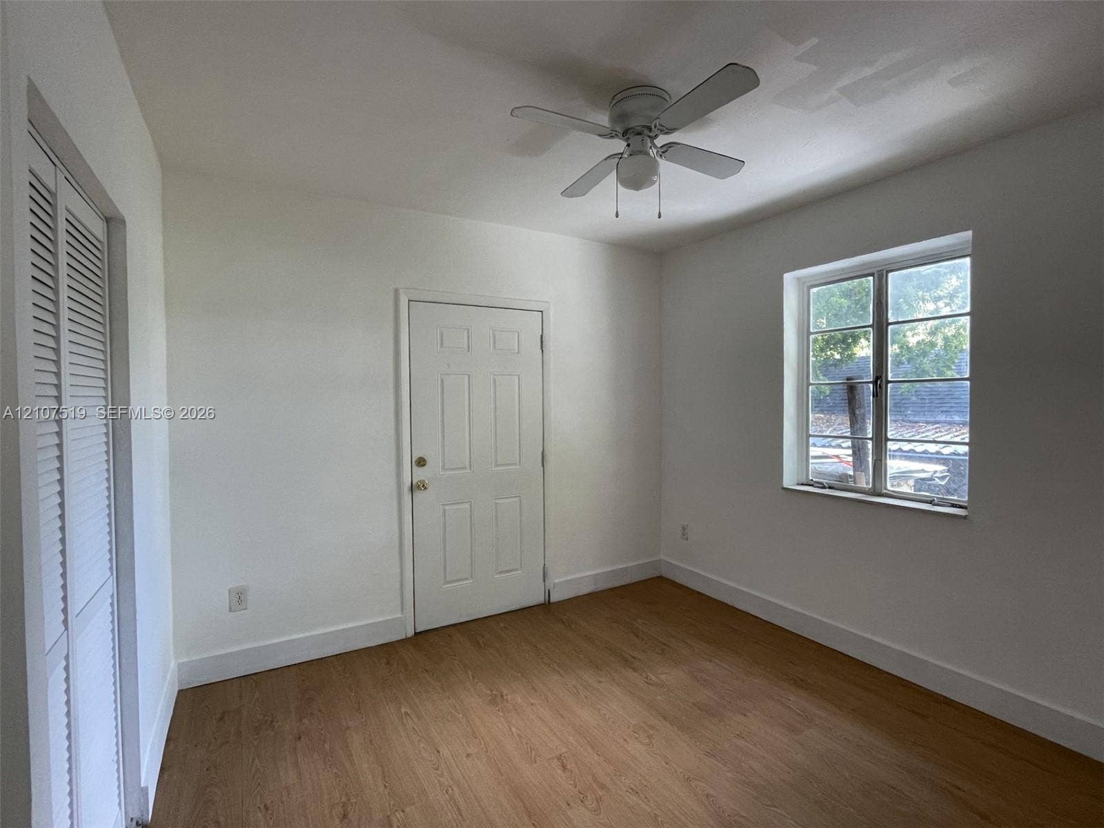 1201 SW 13th Street, #1205, Miami, Miami, FL 33145 Room featuring wood-finish flooring, a multi-pane window, louvered closet doors, and a ceiling fan with integrated light fixture