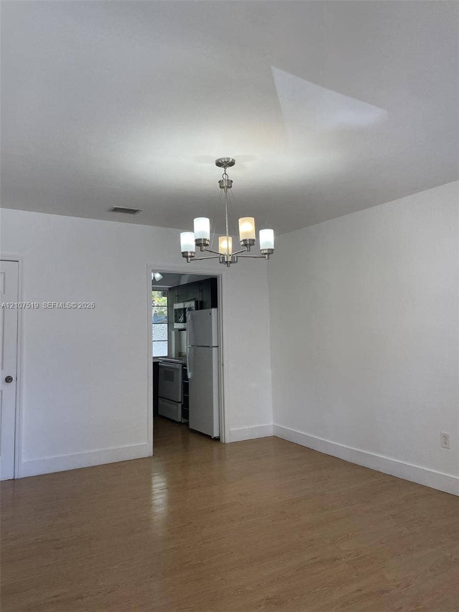 1201 SW 13th Street, #1205, Miami, Miami, FL 33145 Neutral interior space featuring wood-finish flooring, a five-arm chandelier with frosted glass shades, and white wall finishes