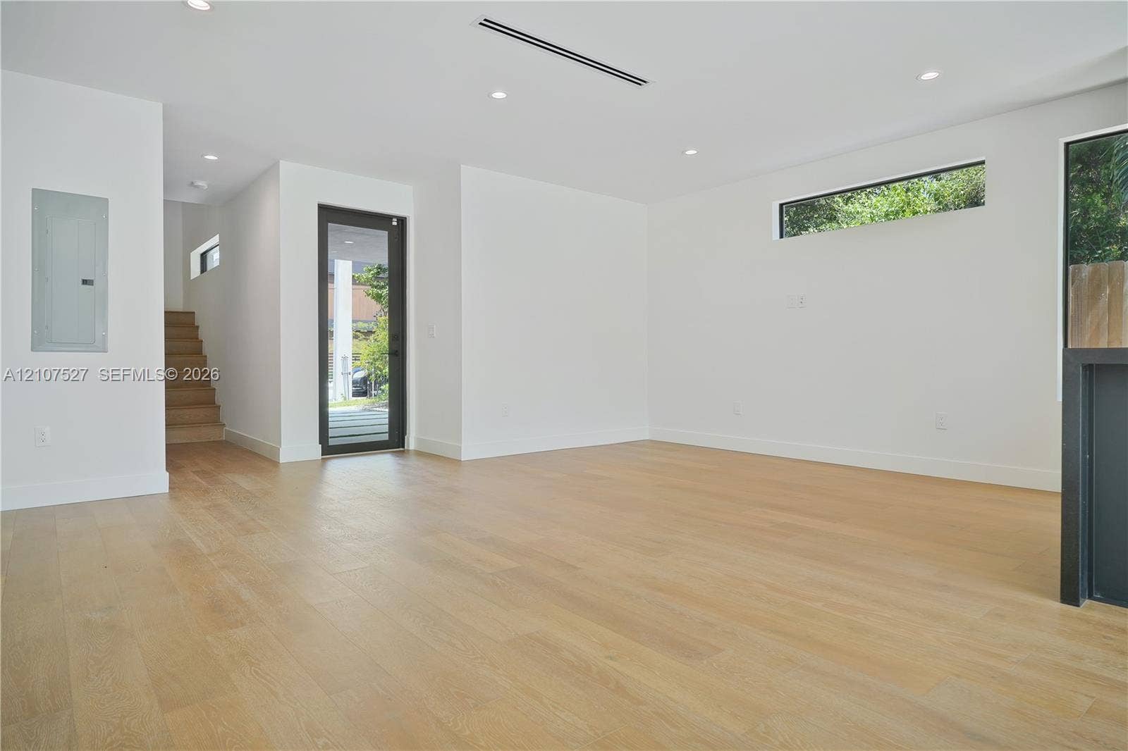 355 NW 50th Street, Miami, FL 33127 Open-concept interior featuring light wood-finish flooring, recessed lighting, clerestory windows, and a glass-paneled exterior door
