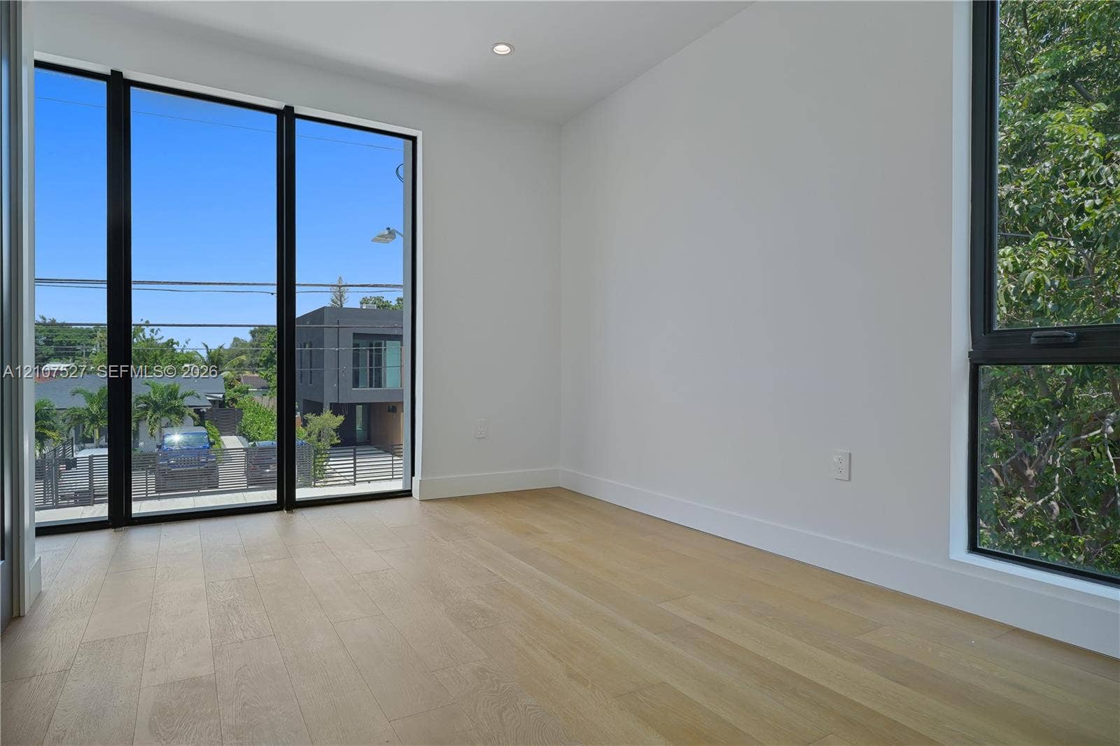 355 NW 50th Street, Miami, FL 33127 Interior space featuring wood-finish flooring, floor-to-ceiling windows with black frames, and recessed lighting