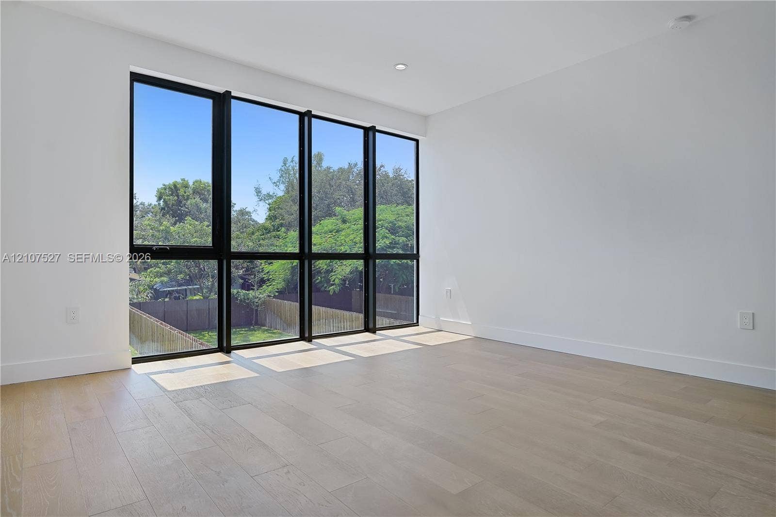 355 NW 50th Street, Miami, FL 33127 Floor-to-ceiling black-framed windows, wood-finish flooring, and recessed ceiling lighting