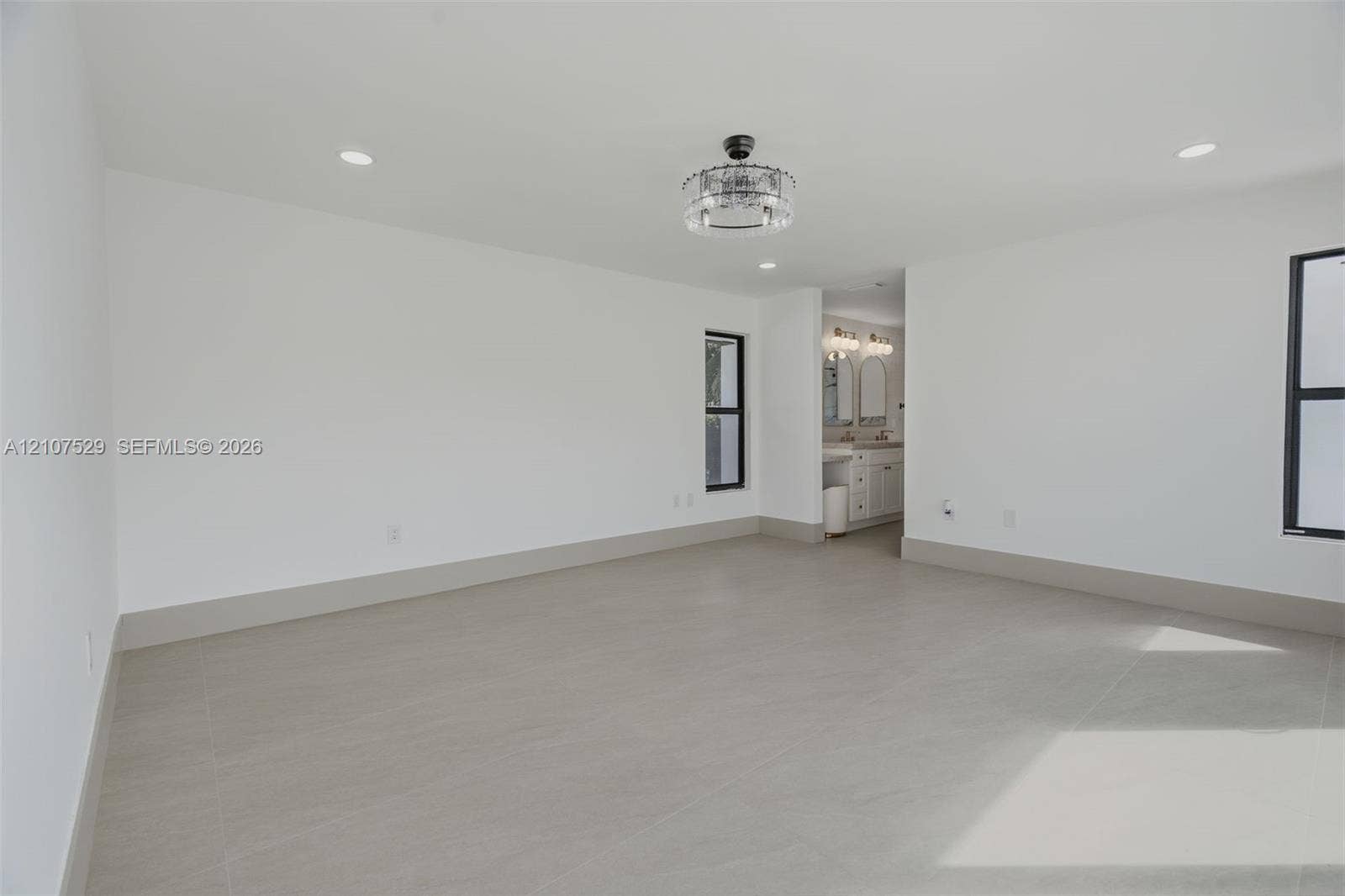 Interior space featuring large-format tile flooring, multi-panel sliding glass doors, recessed lighting, and a drum-style ceiling fixture