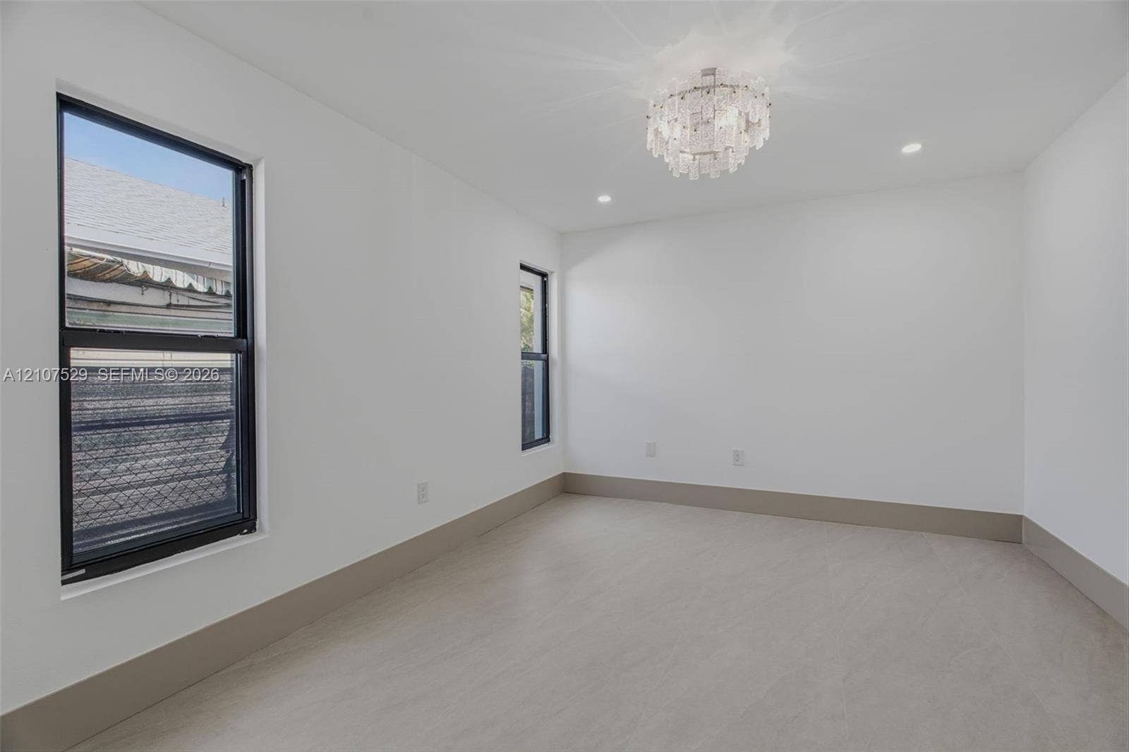 Neutral-toned tile flooring, recessed lighting, ornate central pendant fixture, black-framed windows, and built-in closet with panel doors