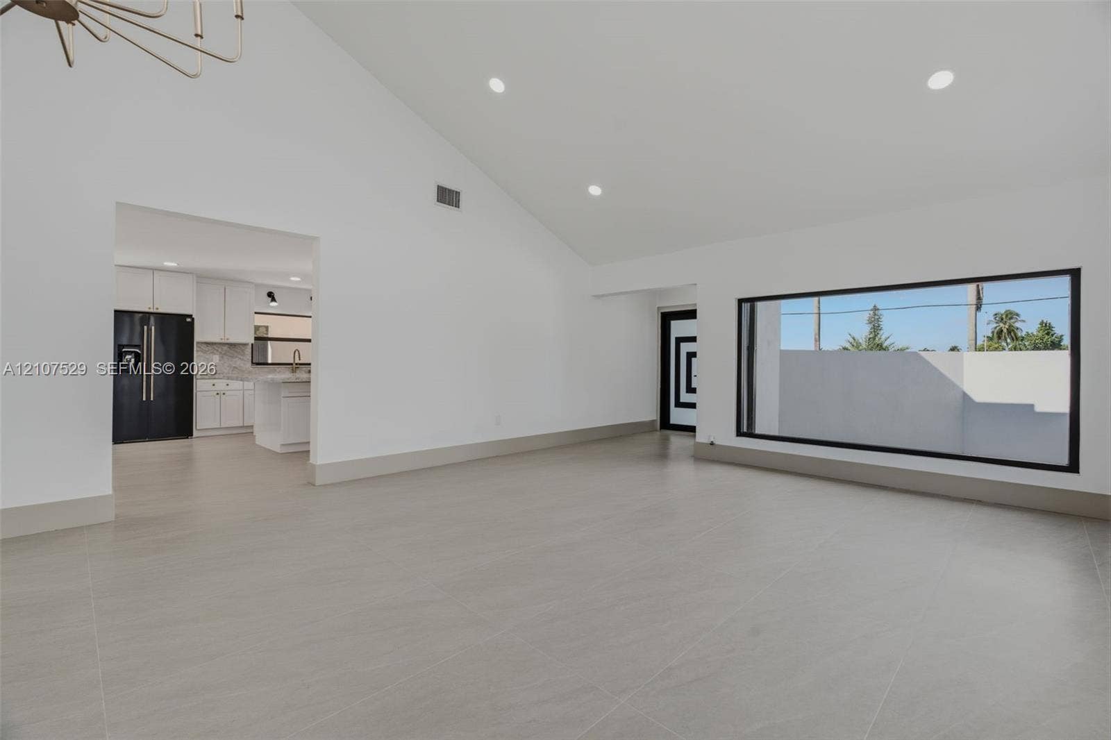 Private patio featuring large-format tile flooring, high perimeter masonry walls, a dark metal privacy fence, and wood-finish ceiling soffit