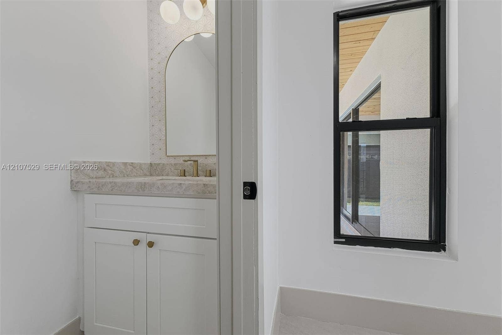 Interior space featuring large-format tile flooring, a two-panel door with matte black hardware, and an elongated porcelain toilet