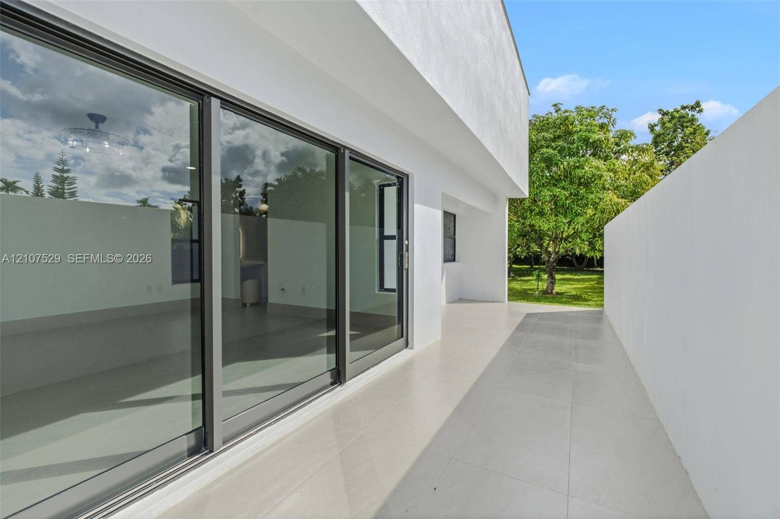 Covered patio featuring large-format porcelain tile flooring and smooth white stucco exterior wall finishes