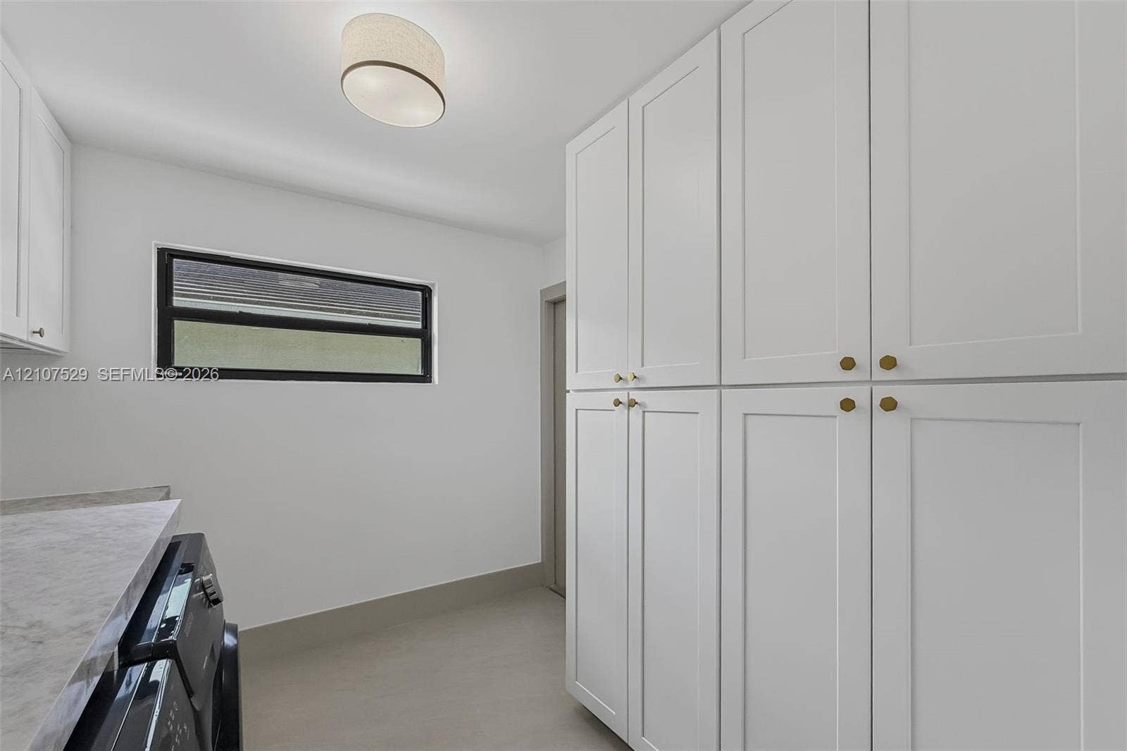 Laundry area featuring white shaker-style cabinetry, stone-finish countertops, an undermount sink with a gooseneck faucet, vertical tile backsplash, and natural wood-tone open shelving