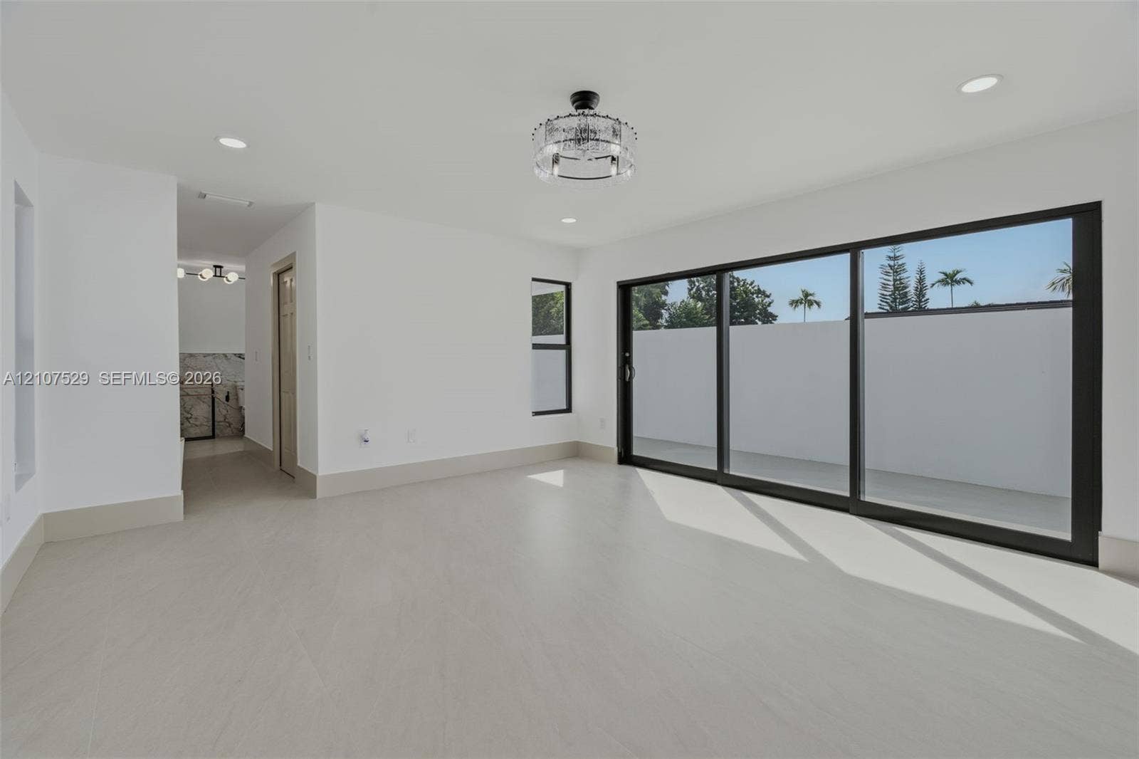 Spacious interior featuring large-format tile flooring, recessed lighting, a modern drum-style flush mount ceiling fixture, and black-trimmed windows
