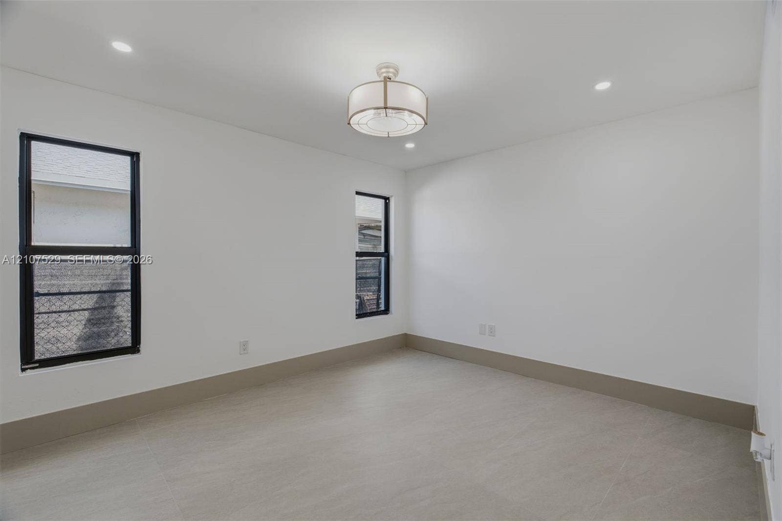 Neutral-toned room featuring a tiered crystal chandelier, wood-finish flooring, recessed lighting, double-panel sliding closet doors, and black-framed windows