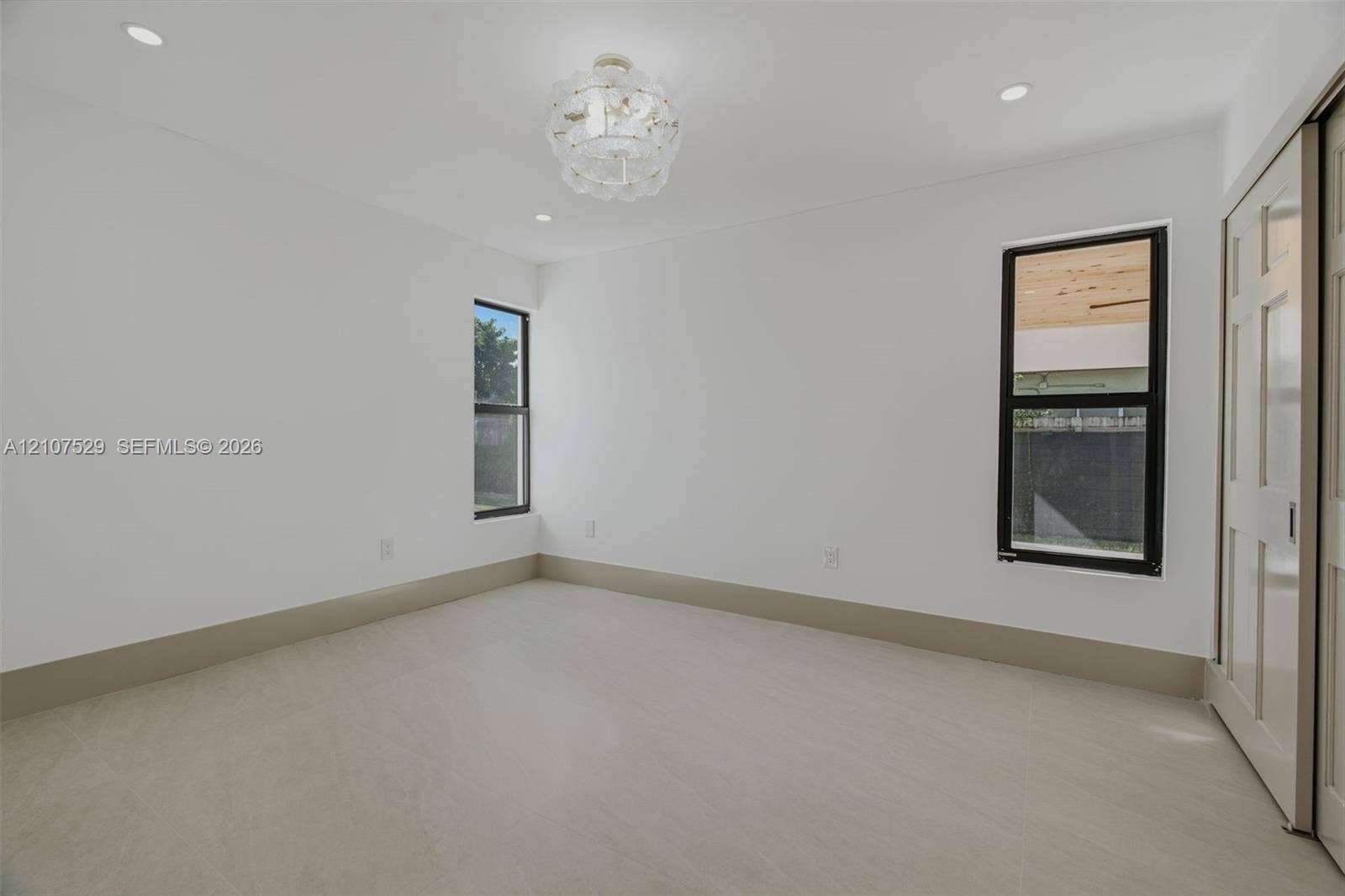 Neutral-toned tile flooring, multi-pane sliding closet doors, decorative multi-tiered pendant lighting, and recessed ceiling illumination