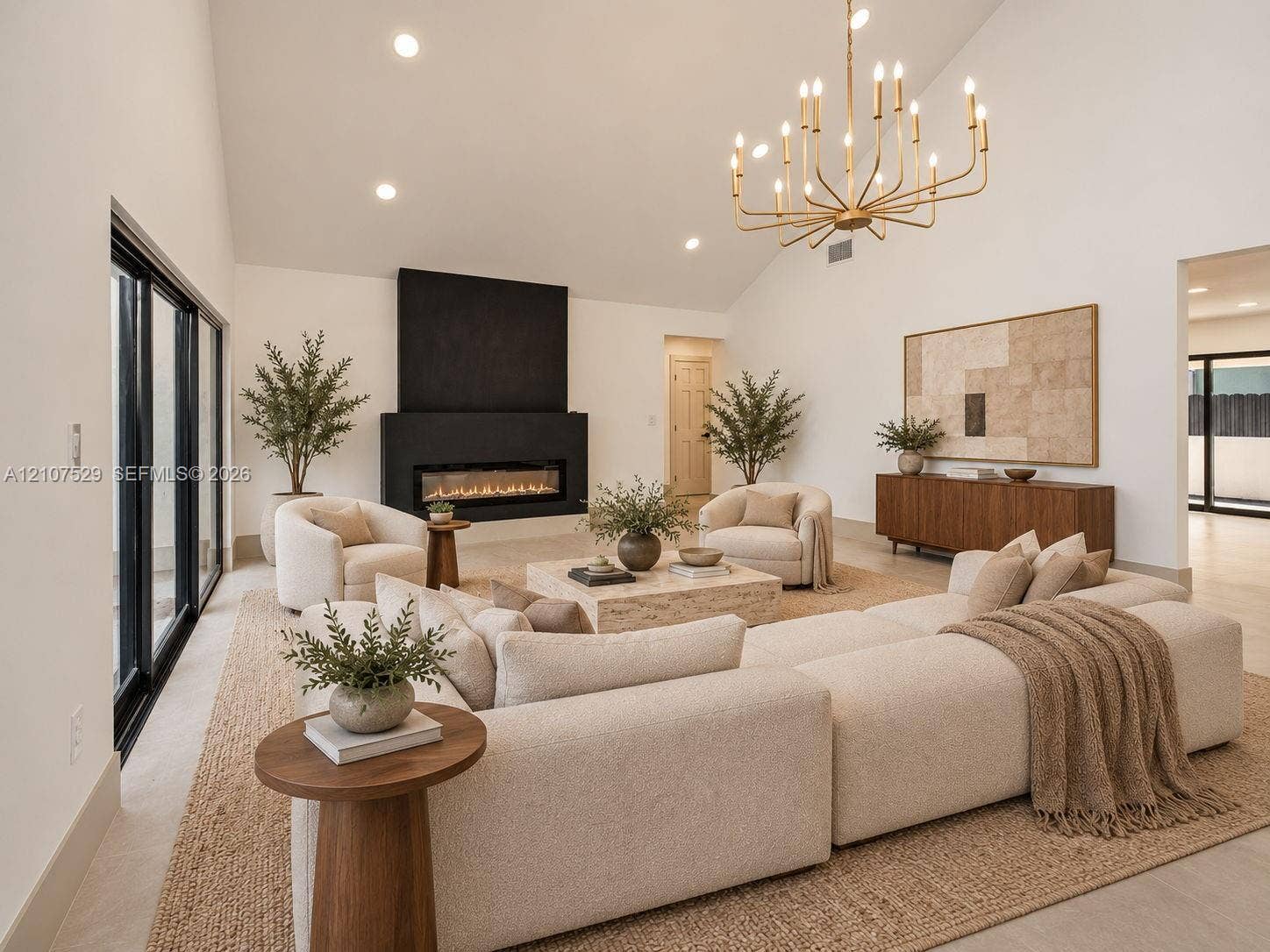 Vaulted ceiling with recessed lighting, floor-to-ceiling black-framed windows, linear fireplace with a matte black surround, and metal multi-tier chandelier