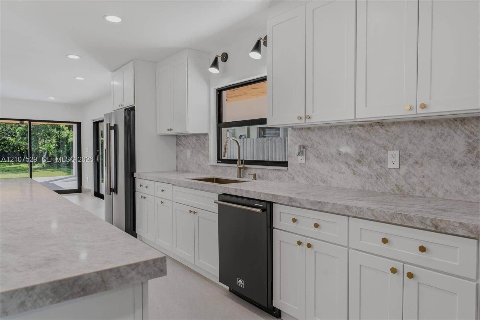 Kitchen featuring shaker-style cabinetry, stone countertops with matching backsplash, a large center island, built-in beverage refrigerator, and recessed lighting