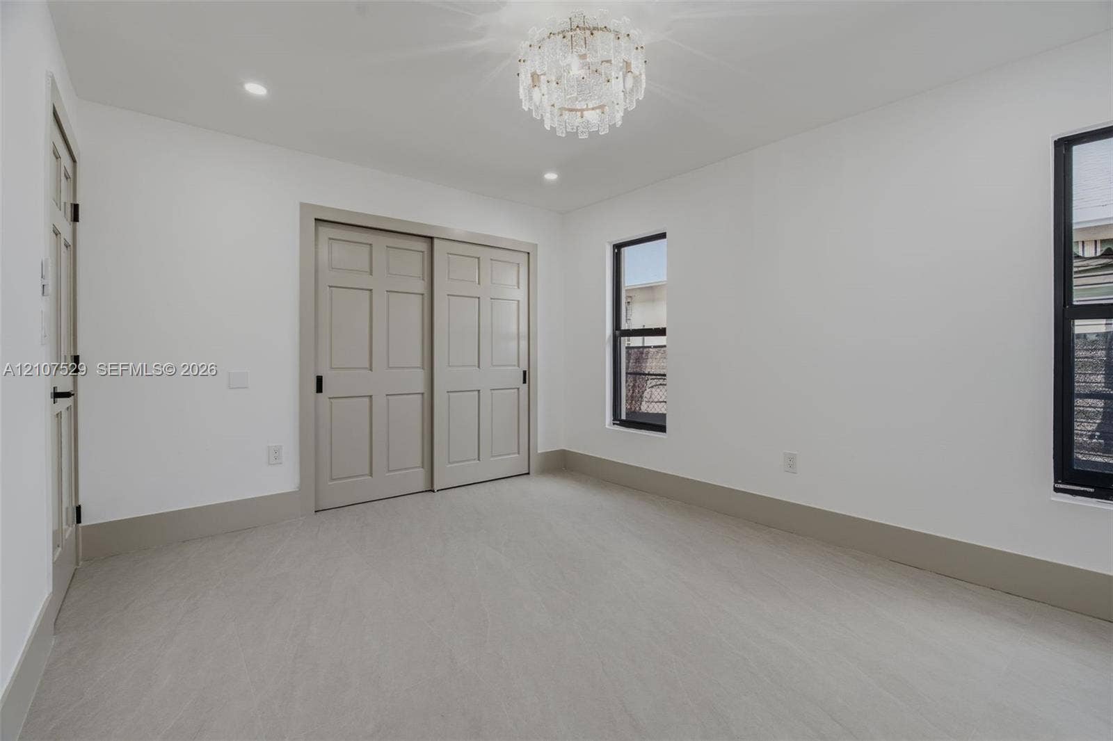Interior space featuring light-toned tile flooring, neutral walls, a tiered crystal-style flush mount ceiling fixture, and recessed lighting