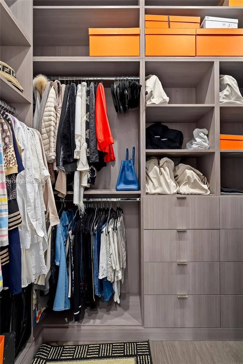 Custom walk-in closet featuring floor-to-ceiling cabinetry, integrated shelving units, multi-level hanging rods, and built-in drawers with polished hardware
