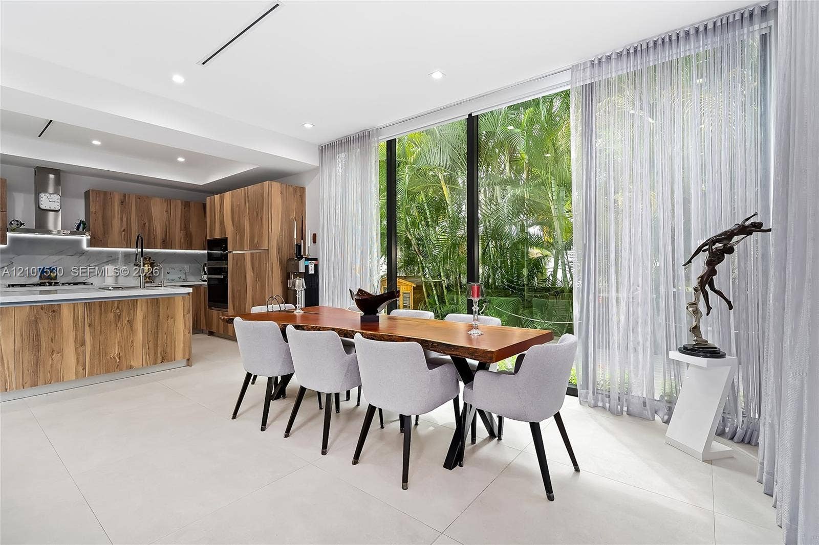 Modern kitchen featuring custom wood-finish cabinetry, stone slab backsplash, integrated built-in appliances, and floor-to-ceiling glass windows