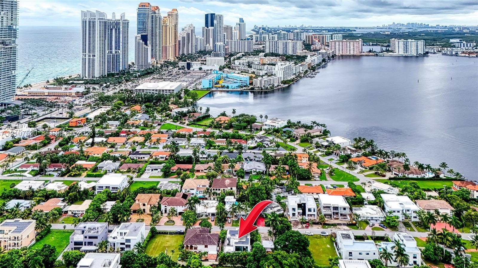Aerial perspective of residential property featuring mature landscaping and a tiled roof, positioned within an urban coastal environment