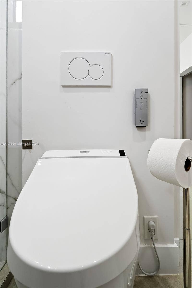 Wall-mounted, dual-flush actuator plate, electronic smart toilet with integrated control panel, and adjacent marble-patterned tile wall finish