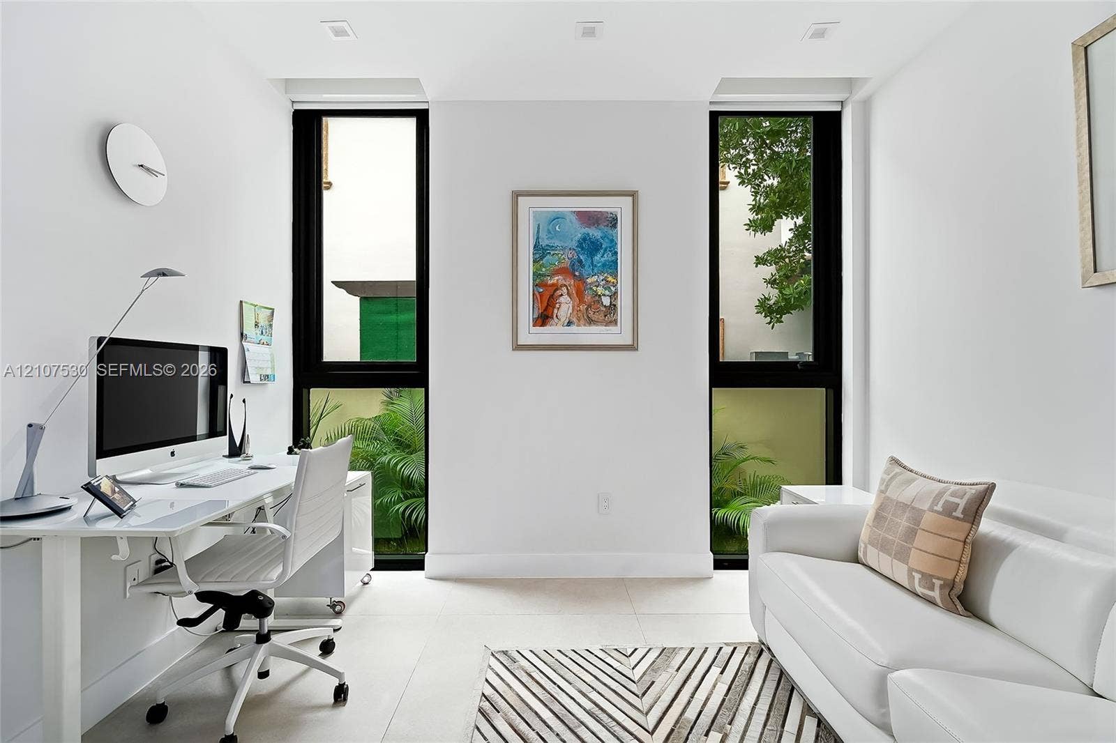 Bright room featuring large, floor-to-ceiling windows with black frames, recessed ceiling lighting, and light-toned tile flooring