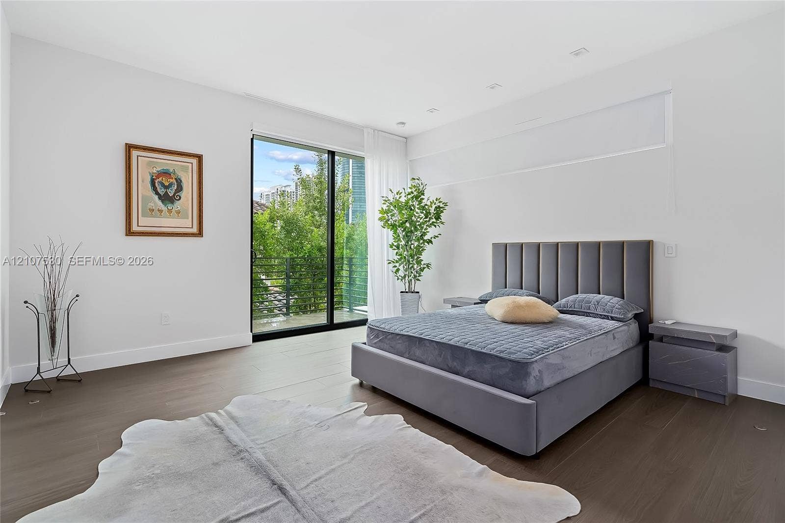 Room featuring wood-finish flooring, recessed lighting, and floor-to-ceiling sliding glass doors opening to a balcony with metal railing