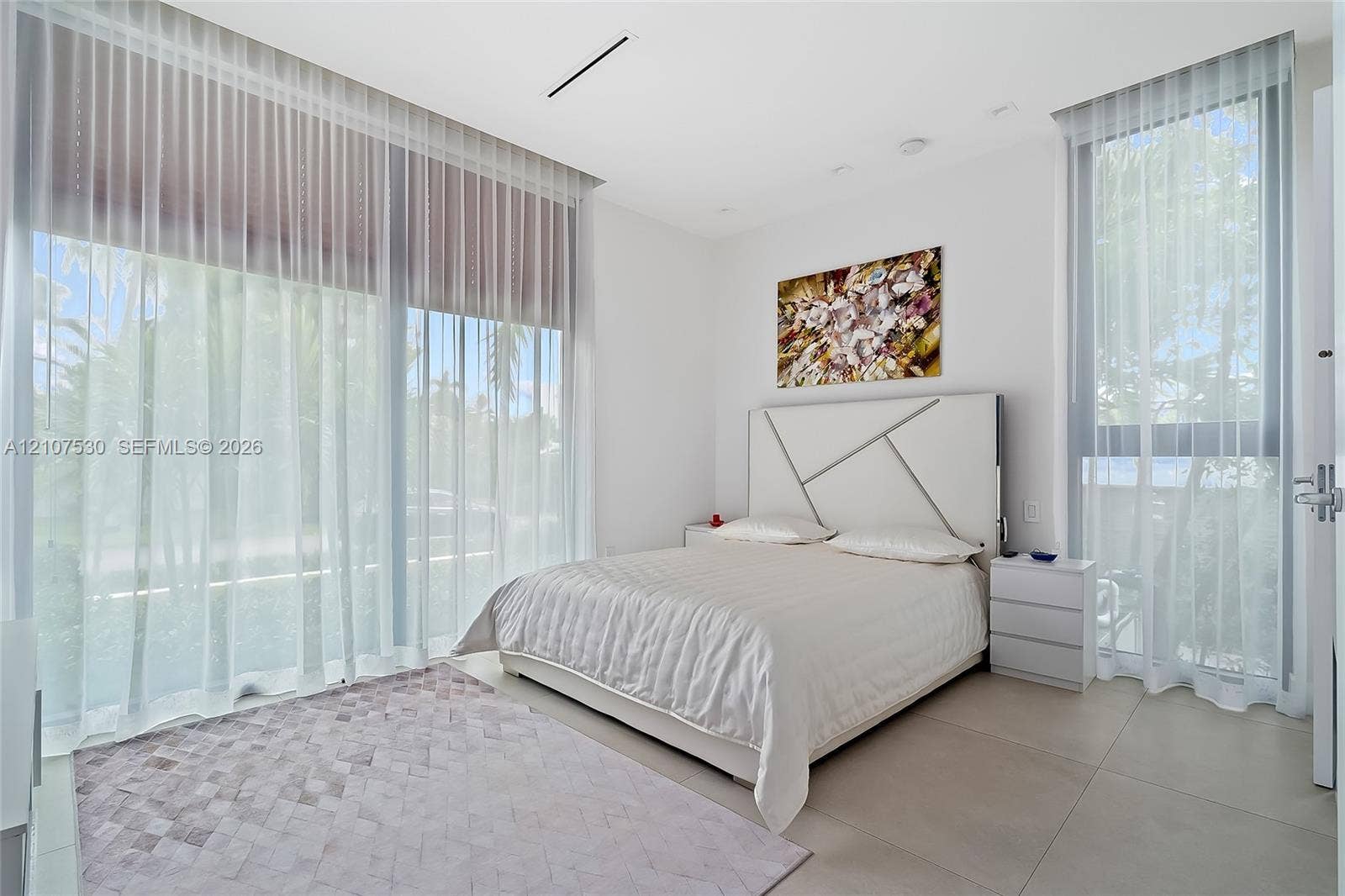 Floor-to-ceiling windows with floor-length treatments, large-format neutral tile flooring, and recessed ceiling lighting