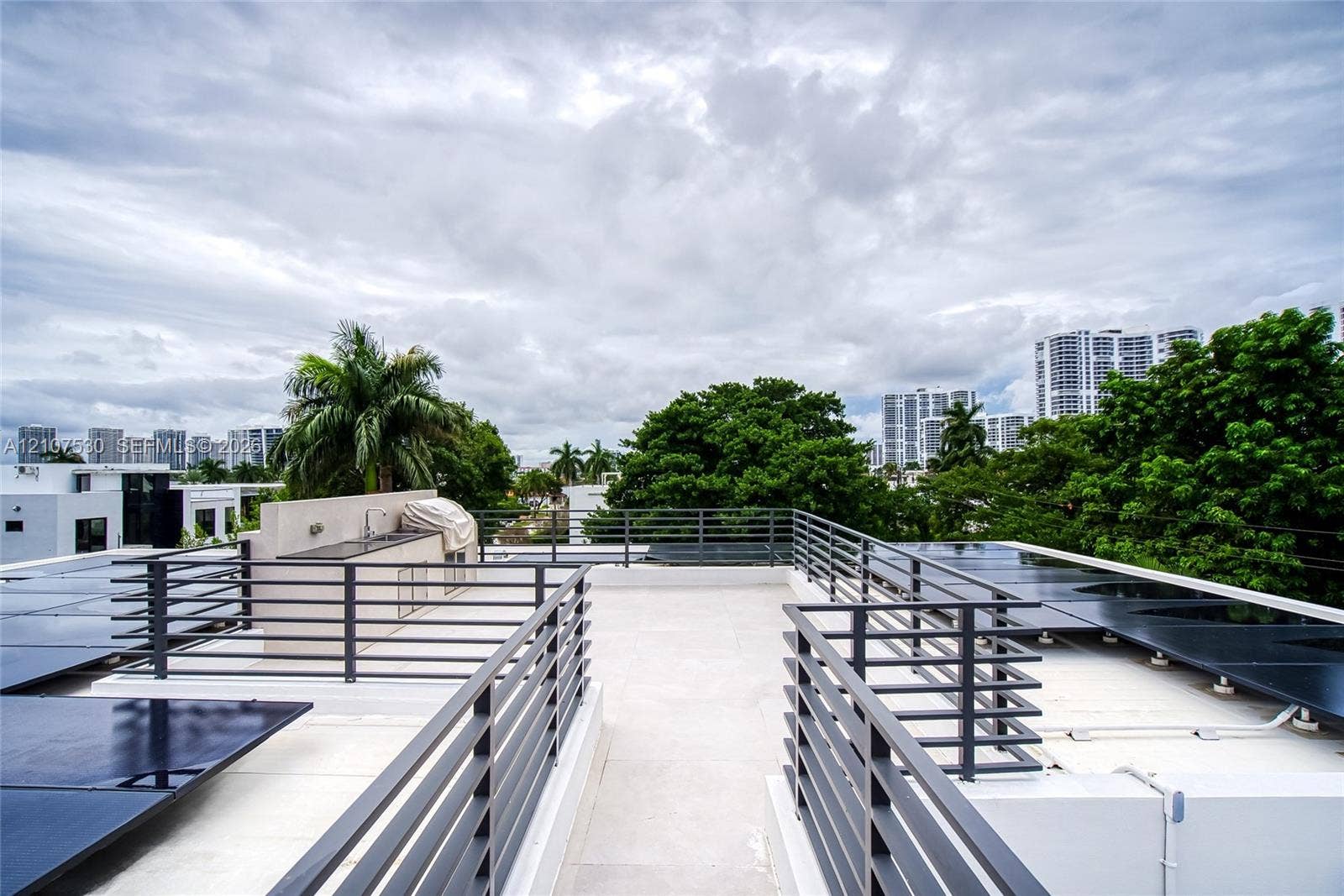 Rooftop terrace featuring light-colored flooring, metal railings, and a built-in outdoor wet bar