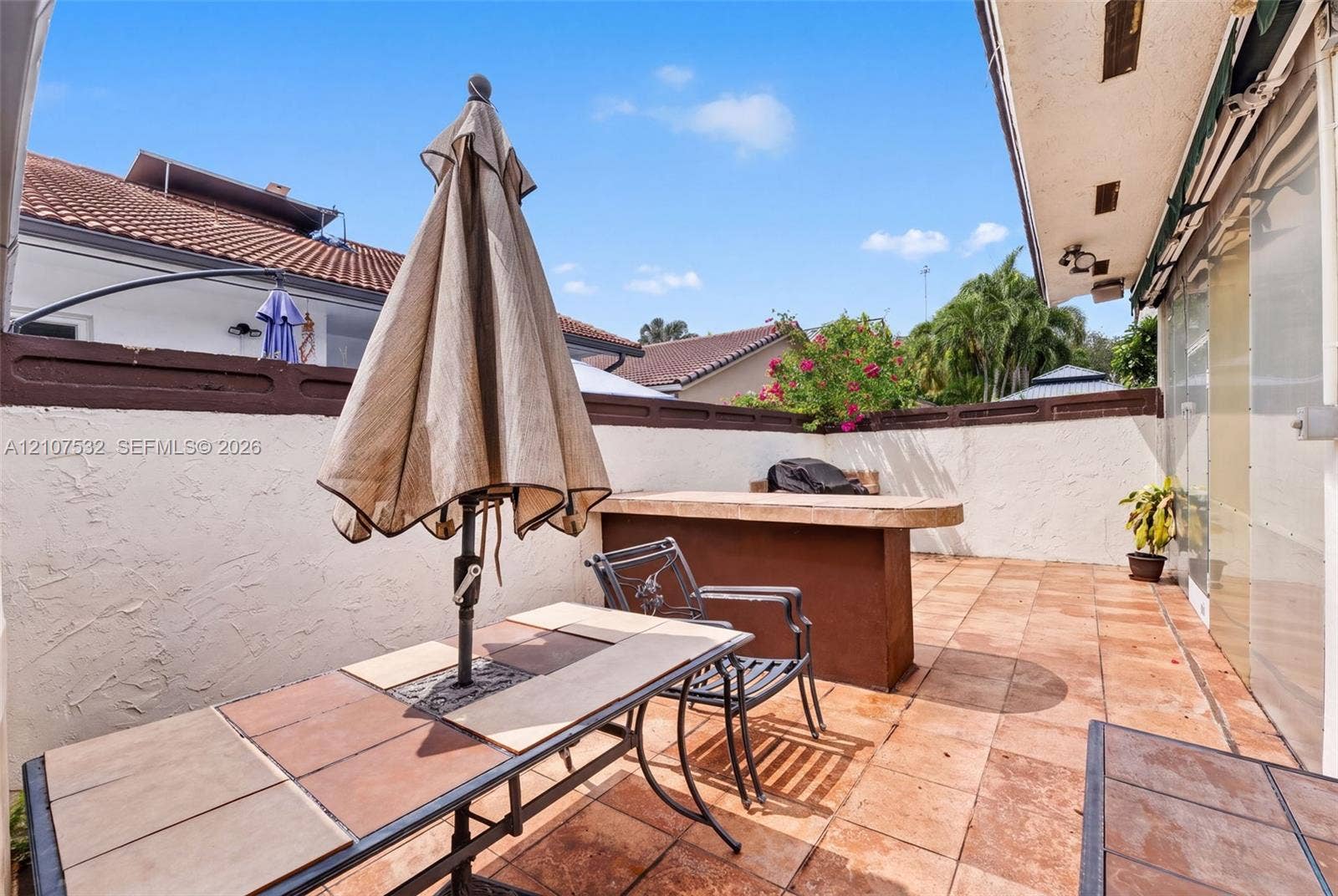 9124 NW 147th Terrace, Miami Lakes, FL 33018 Enclosed patio featuring terracotta-style tile flooring, built-in bar, textured stucco perimeter walls, and an overhead structural awning