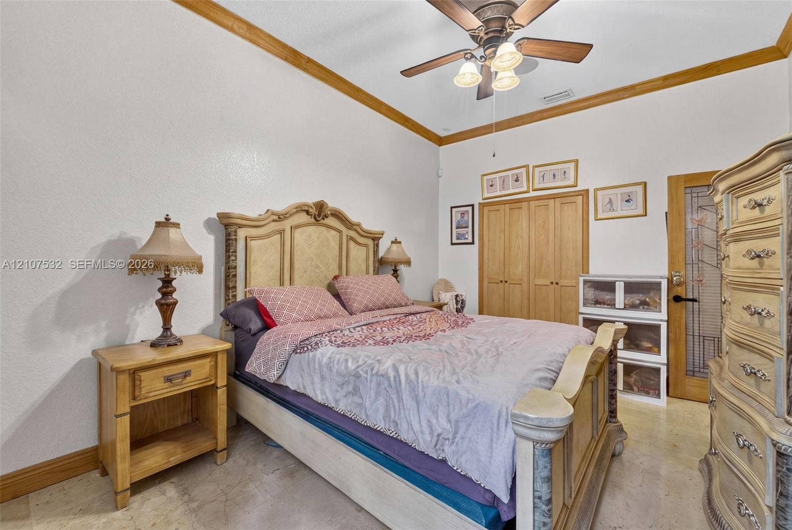 9124 NW 147th Terrace, Miami Lakes, FL 33018 Vaulted ceiling featuring crown molding, neutral stone-finish flooring, ceiling fan with integrated light fixture, built-in wooden closet doors, and a door with decorative glass paneling